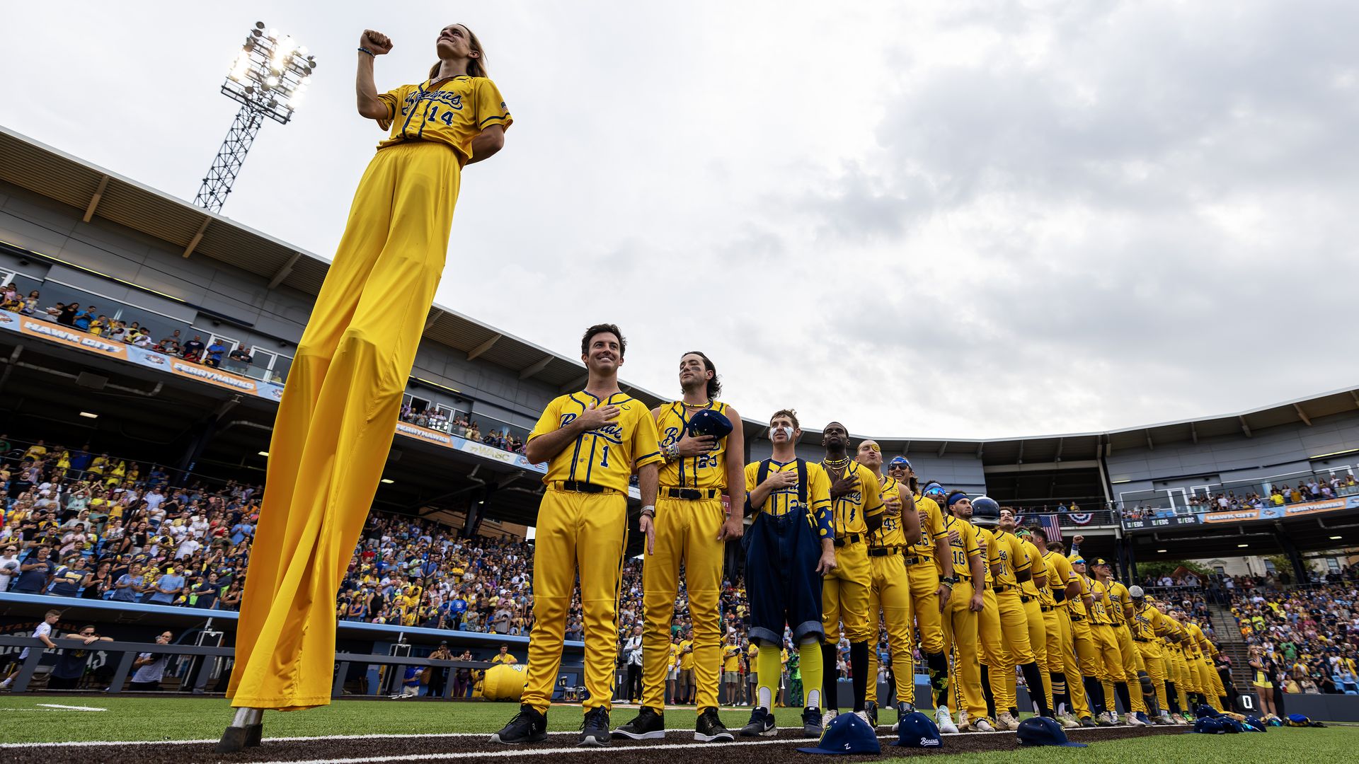 A baseball player in stilts stands for the national anthem with the rest of the Savannah Bananas team