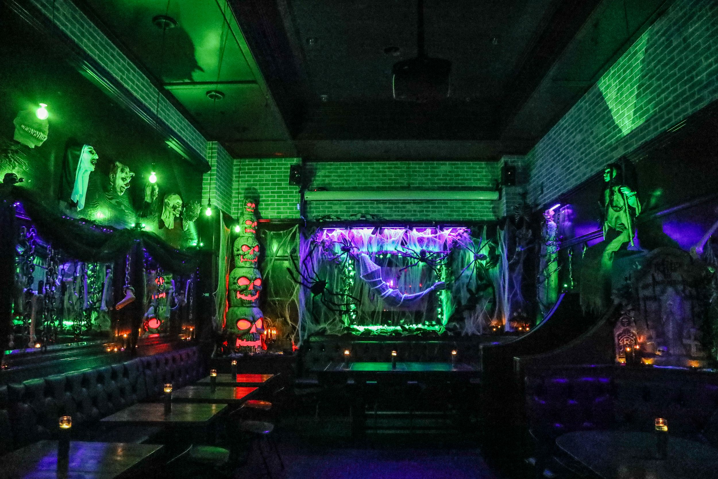 Creepy decor including stacked skulls, cobwebs and green lights.