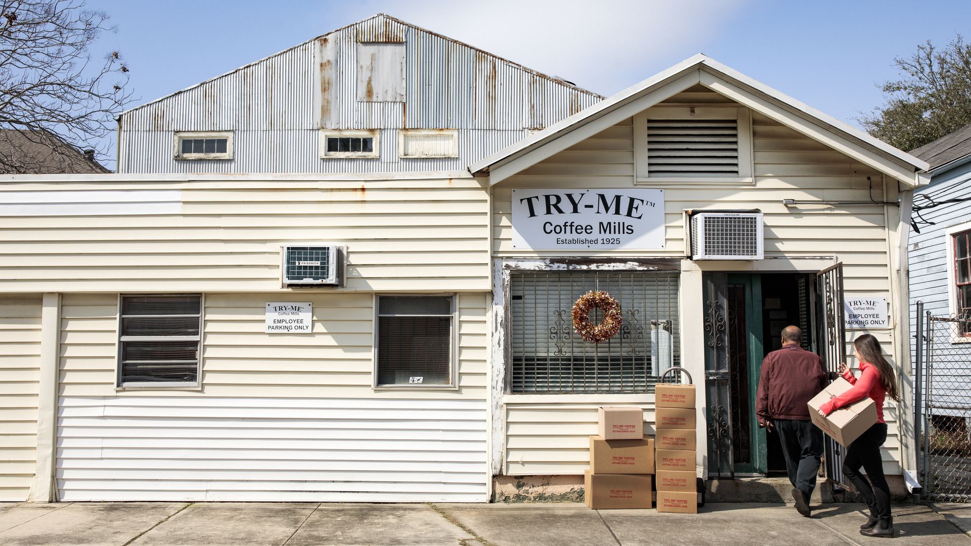 Two people walk into a building with a sign that says Try-Me Coffee Mills.