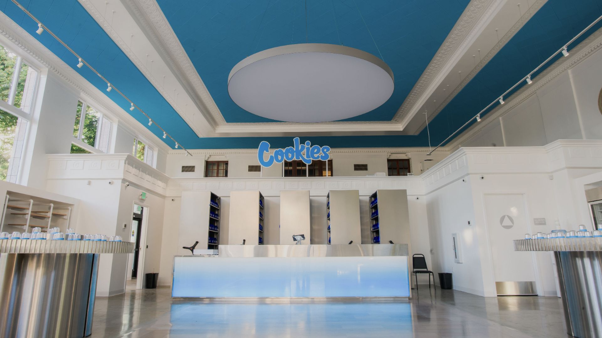 Interior of a retail store that's painted with a blue ceiling and white trim. The logo "Cookies" is centered in the rear of the room. 
