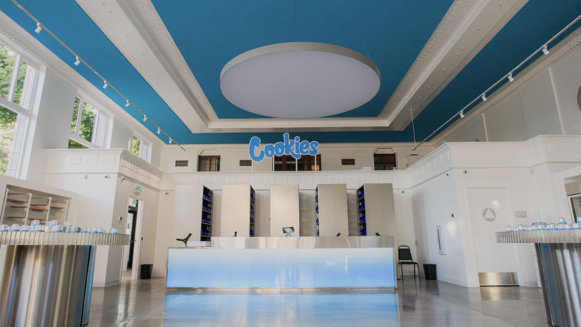 Interior of a retail store that's painted with a blue ceiling and white trim. The logo "Cookies" is centered in the rear of the room.