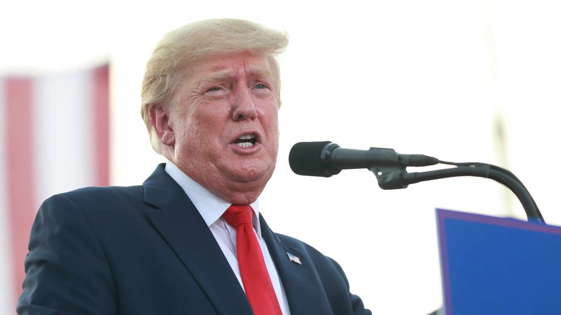 Photo of Donald Trump speaking into a microphone at an outdoor rally