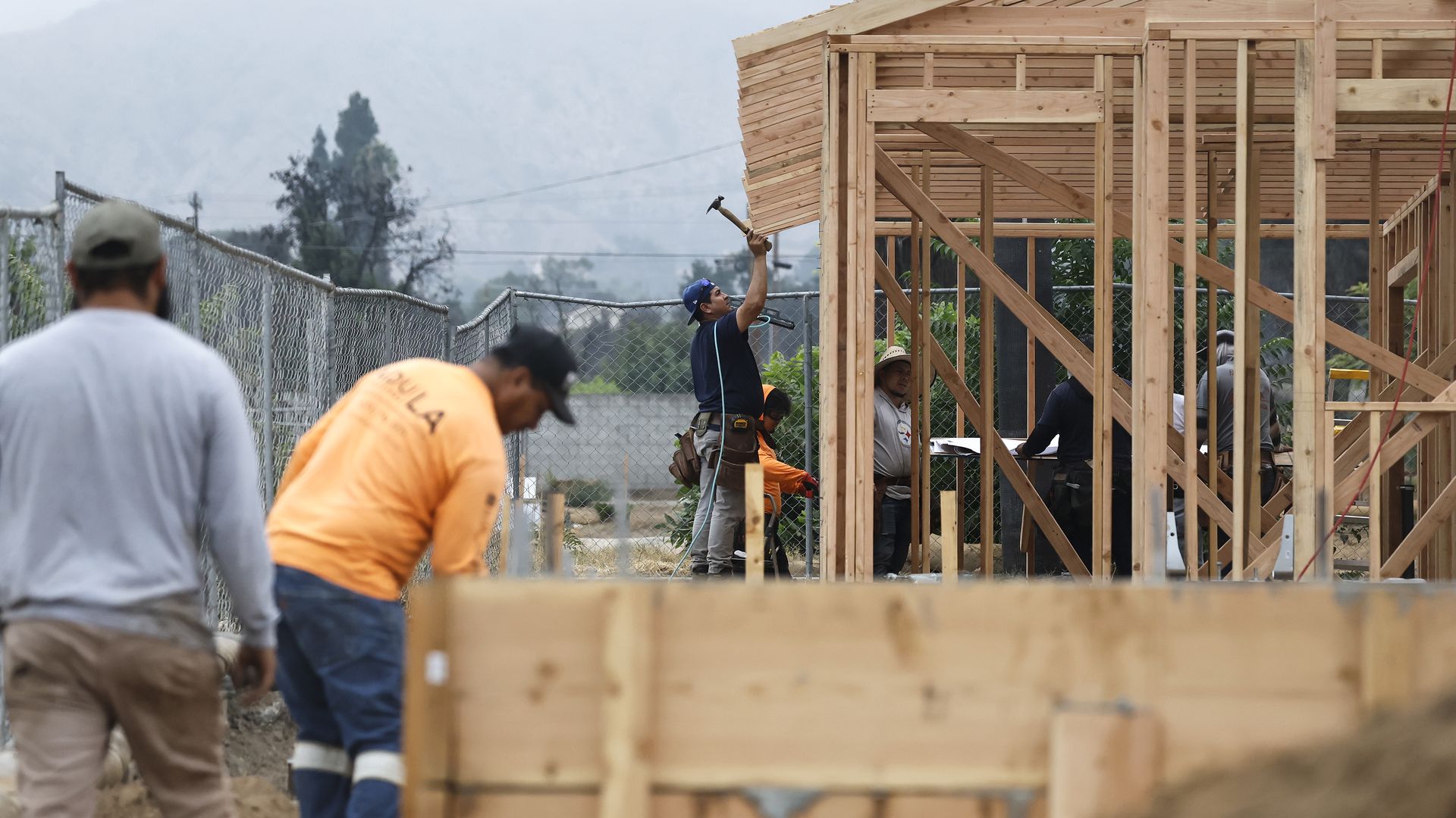 Construction workers build a new home on a property which burned in the Eaton Fire on August 15, 2025 in Altadena, California. 