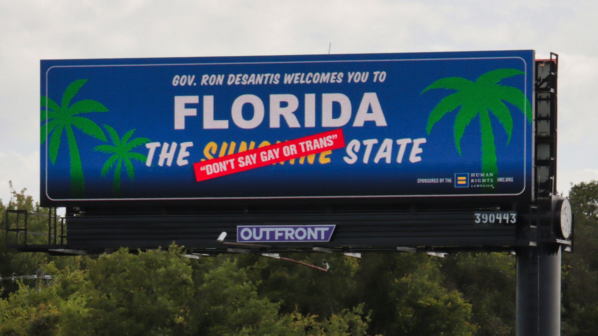 A billboard reading "Gov. Ron DeSantis welcomes you to FLORIDA the ("Sunshine" crossed out) "Don't say gay or trans" state"