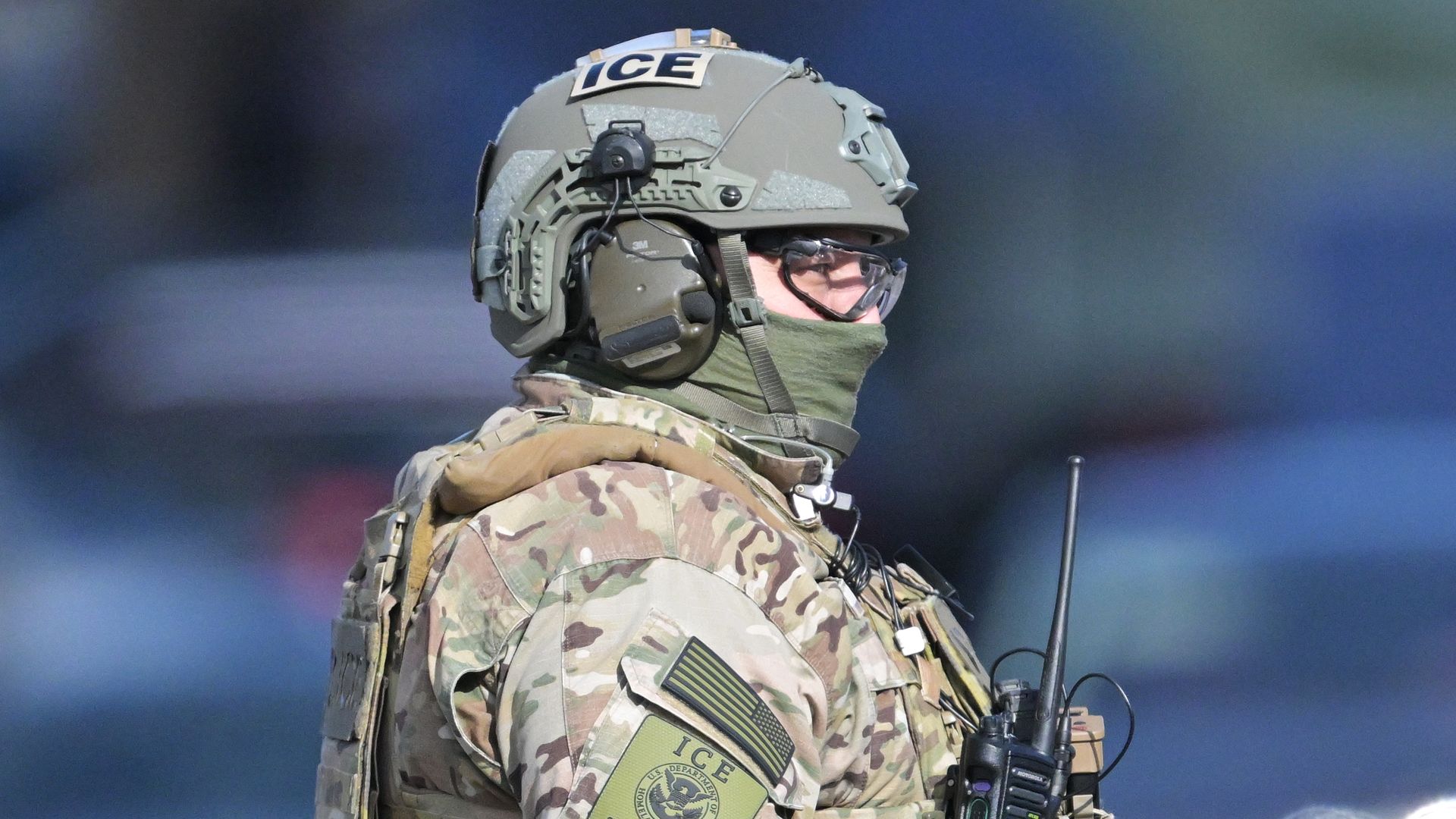A masked man with lenses and full tactical gear, including a helmet with the word ICE spelled on it. 