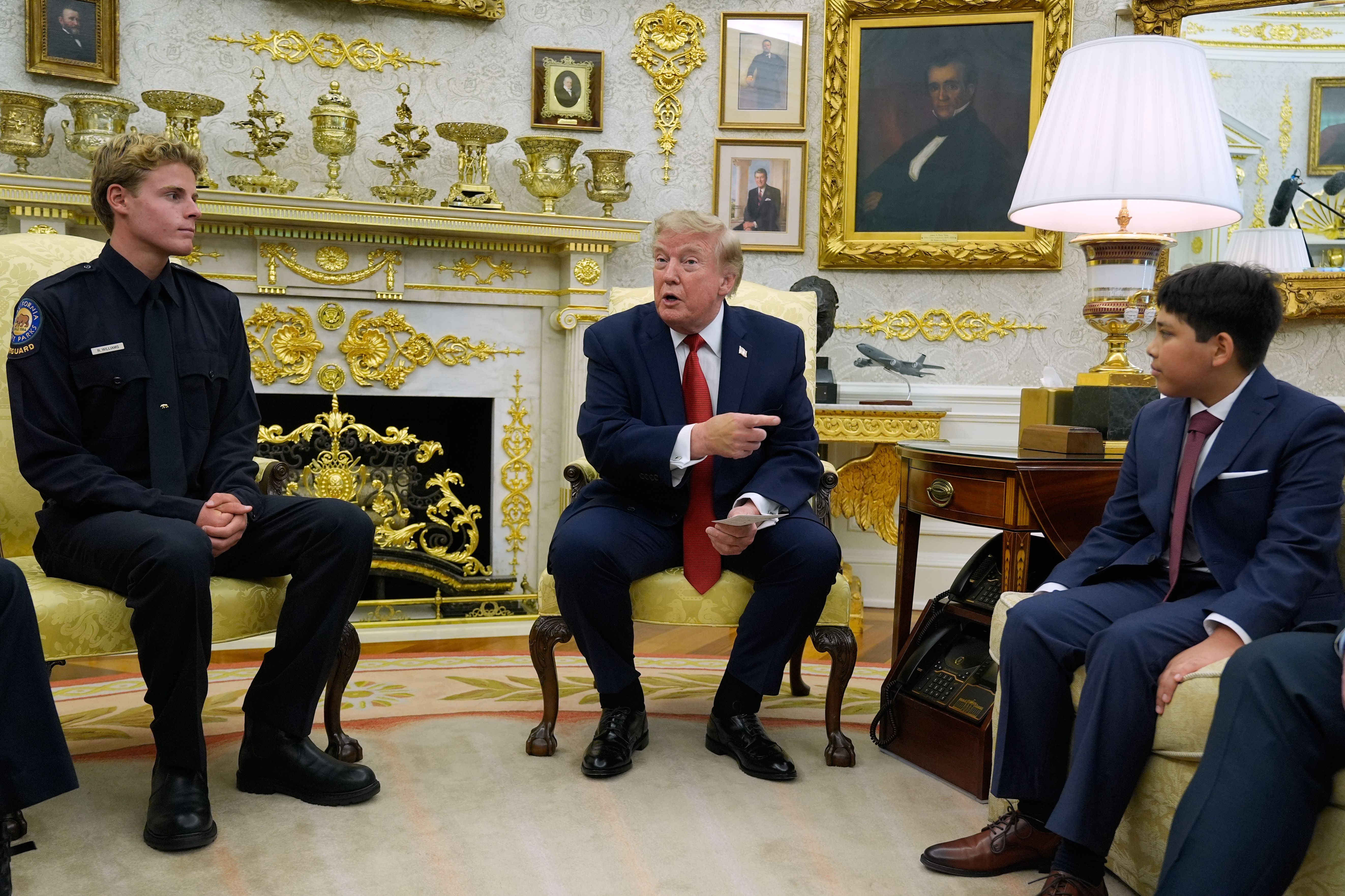 President Trump gestures to Nathaniel Rai, the boy lifeguard Ryder Williams, left, saved as they meet in the Oval Office yesterday.
