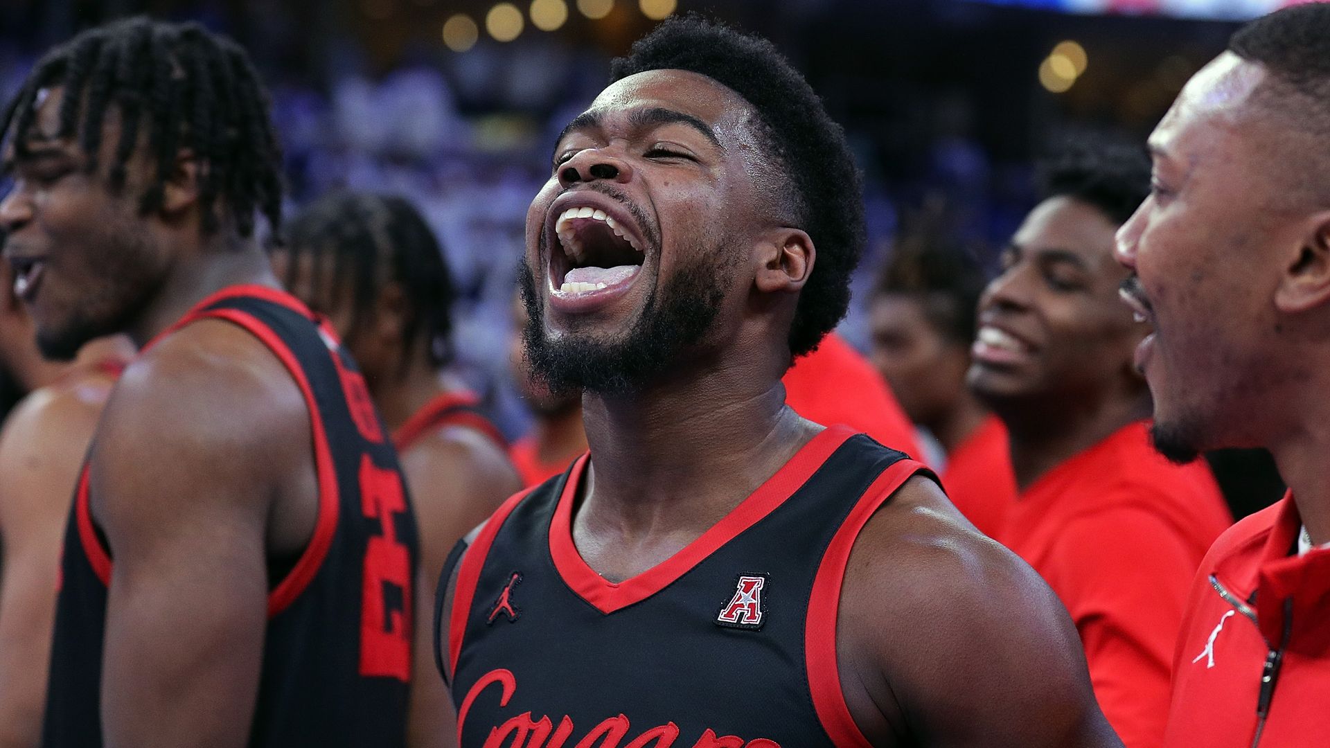 UH Cougars men's basketball player Jamal Shead, wearing a black and red jersey, shouts after scoring a game-winning point