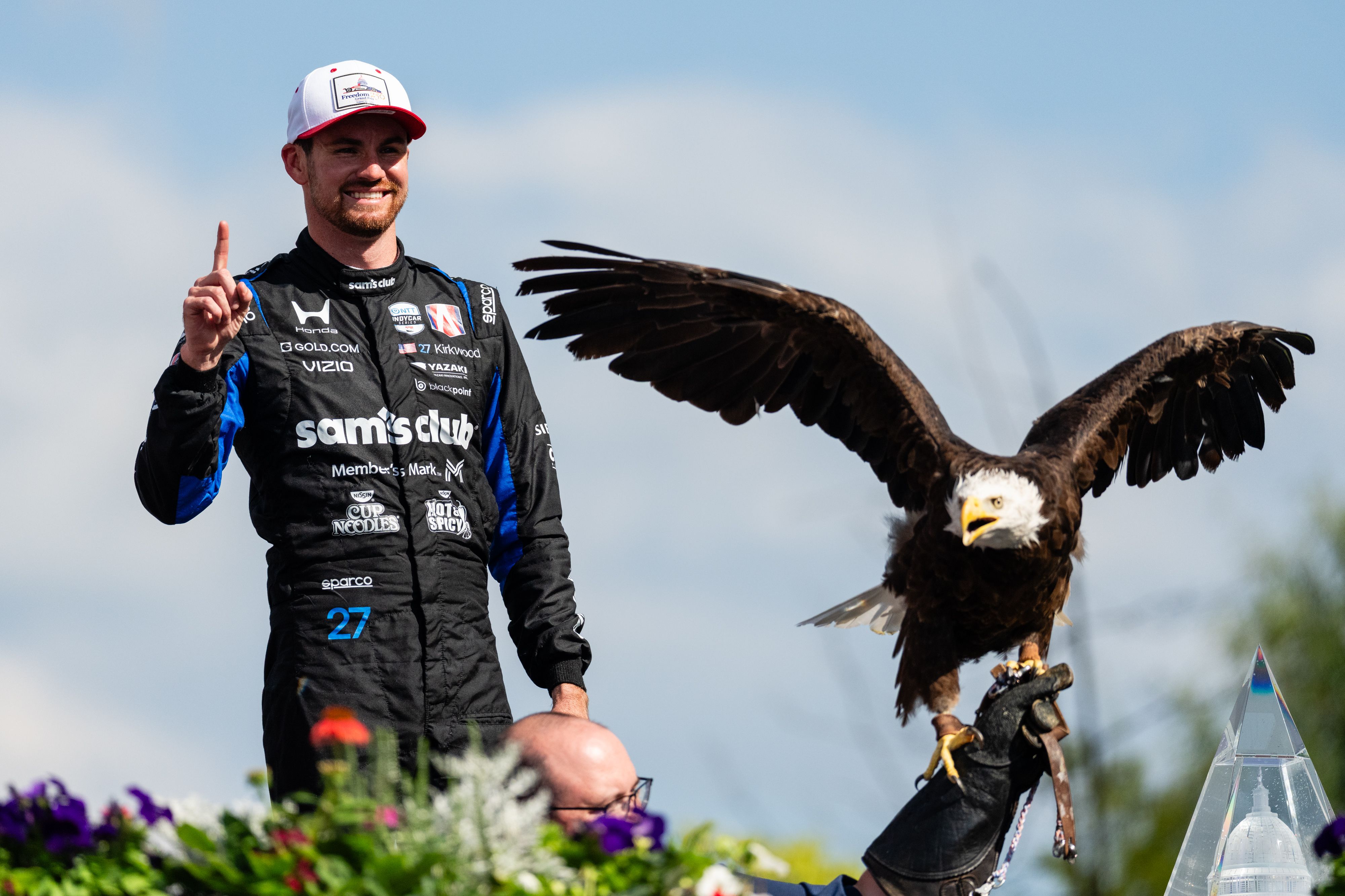 Kyle Kirkwood holds up a #1 as he stands next to a bald eagle
