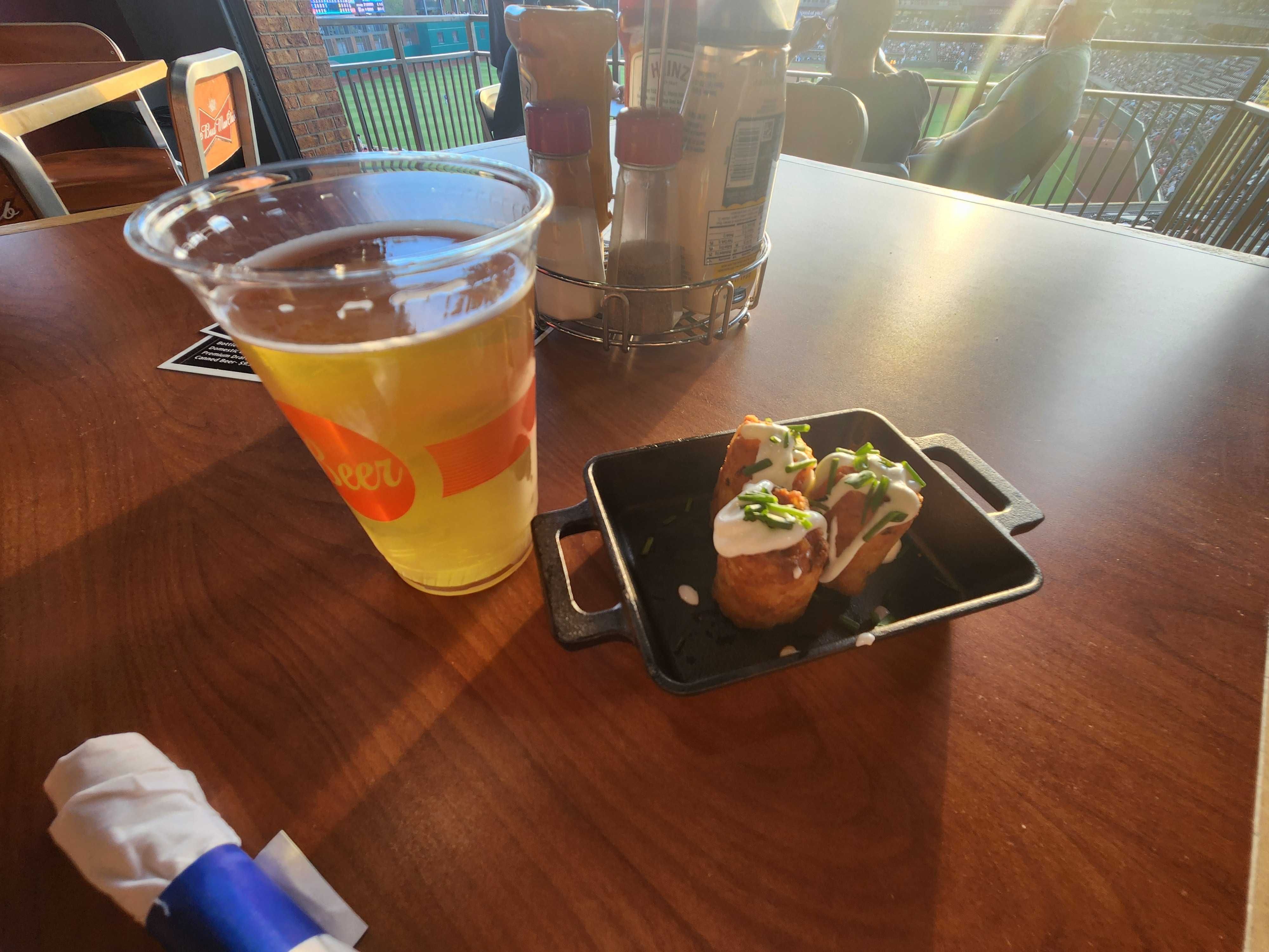 Three tater tots and a beer on a table.