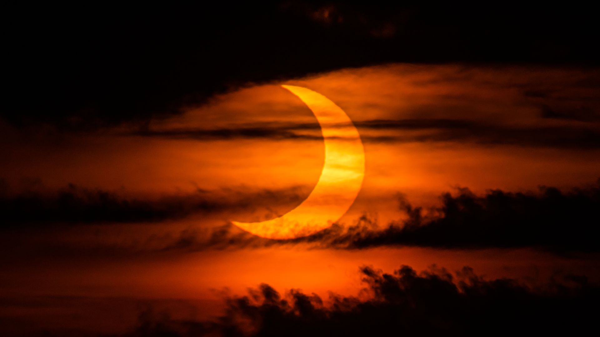 A reddish sky and glowing crescent are shown with darkness on the edges of the picture.
