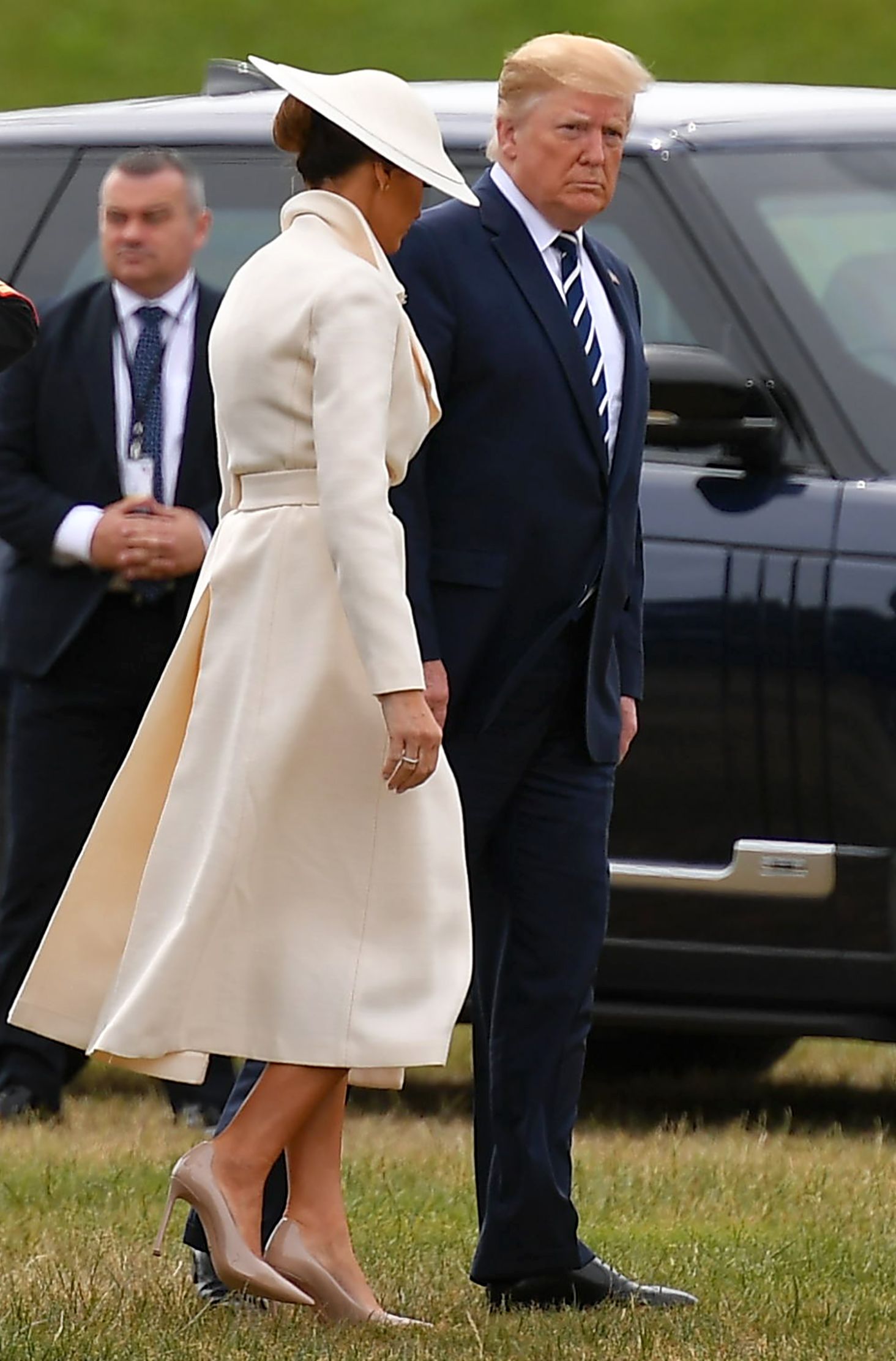 US President Donald Trump (R) and First Lady Melania Trump (C) walk to their vehicle after disembarking from the Marine One helicopter after arriving at Southsea Castle.
