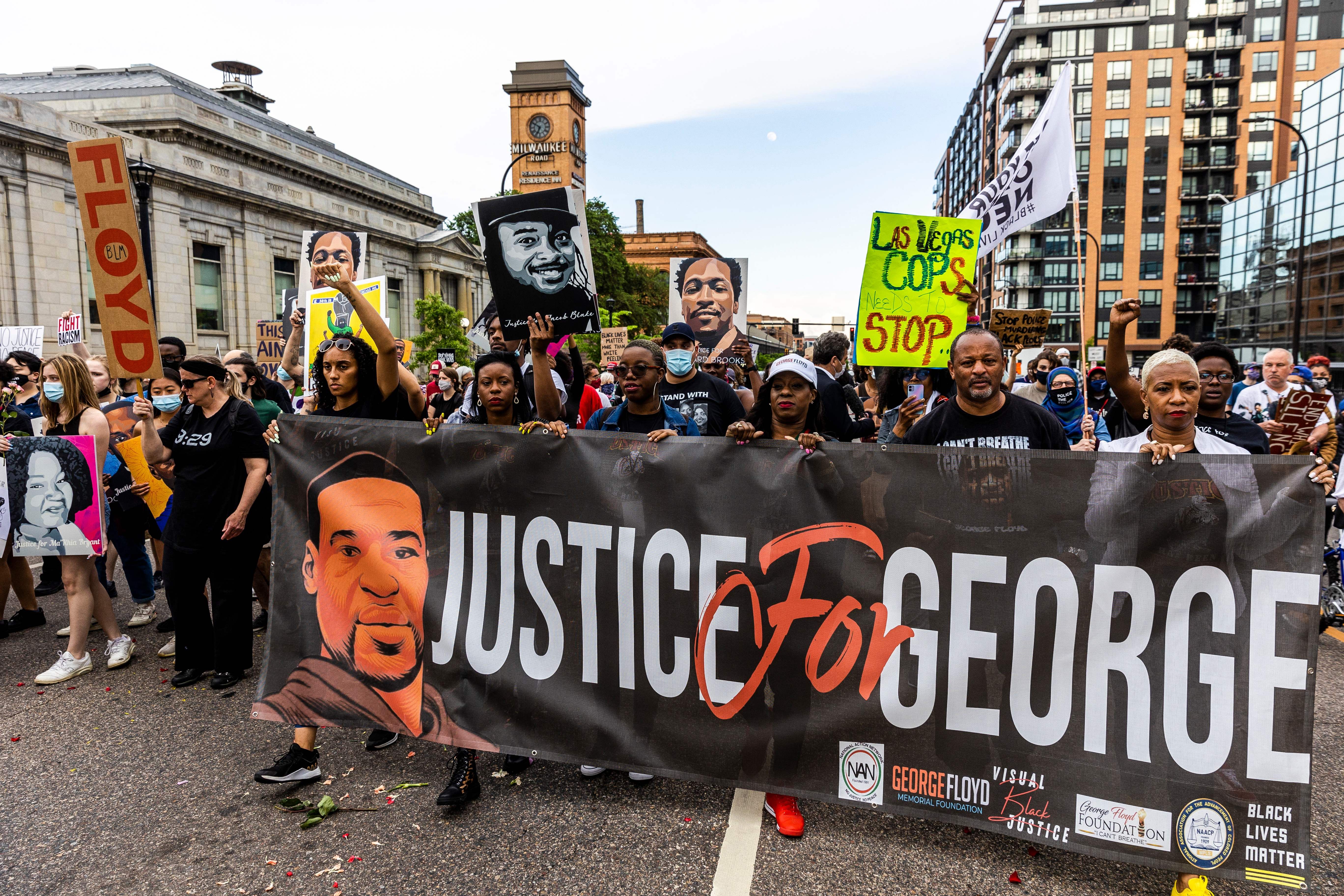 People hold signs and a banner as they march during an event in remembrance of George Floyd in Minneapolis, Minnesota, on May 23