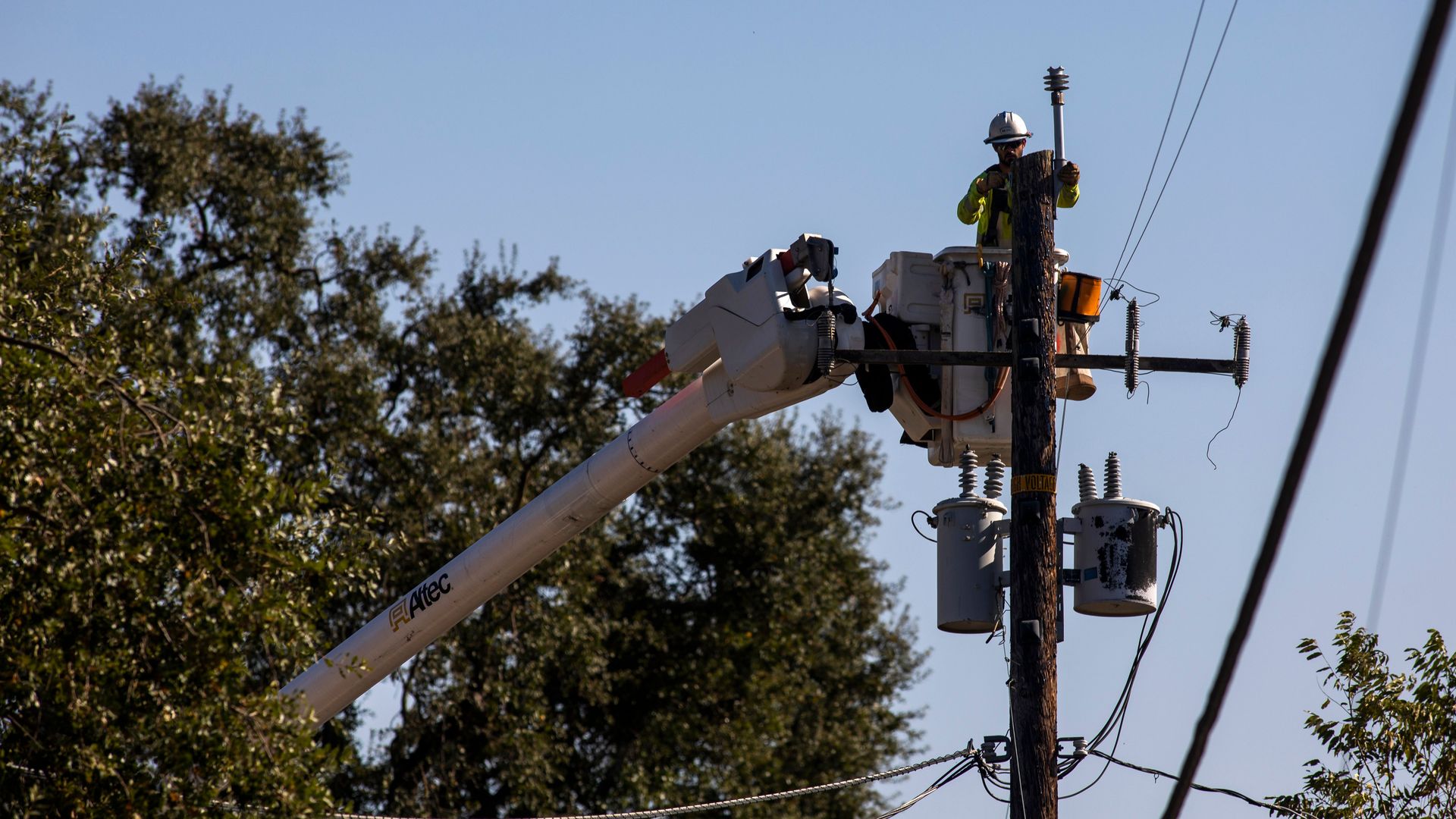 A PG&E contractor works on utility poles