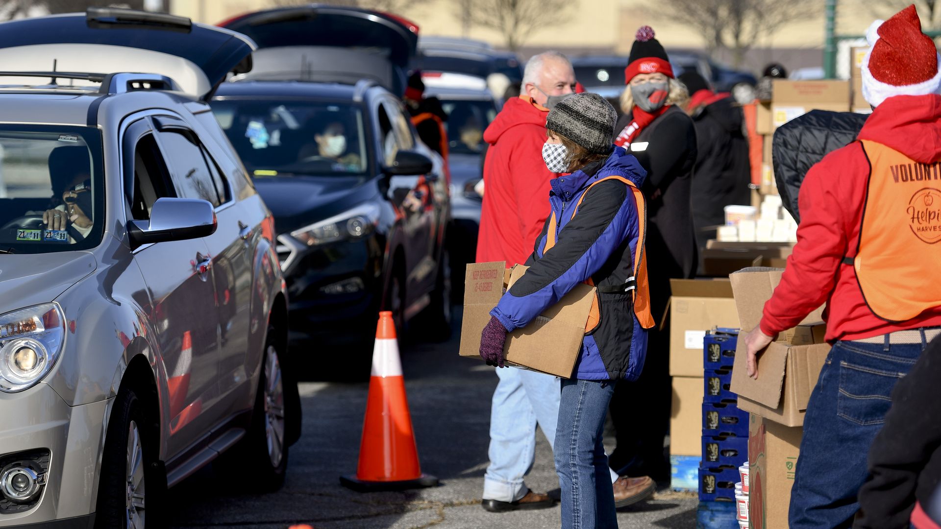 Volunteers distribute food as people drive through in cars.