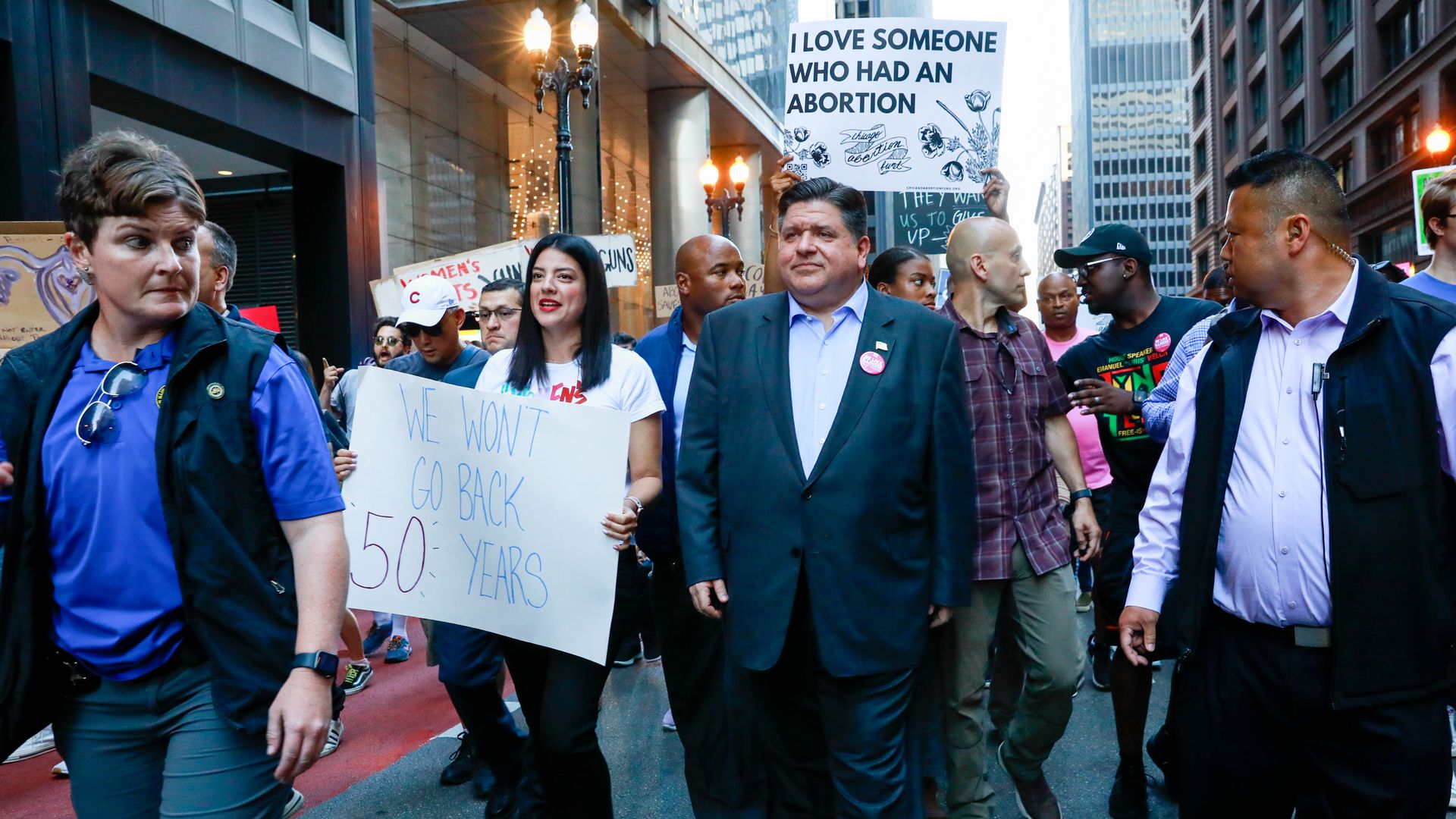 Photo of protesters with signs marching in street. 