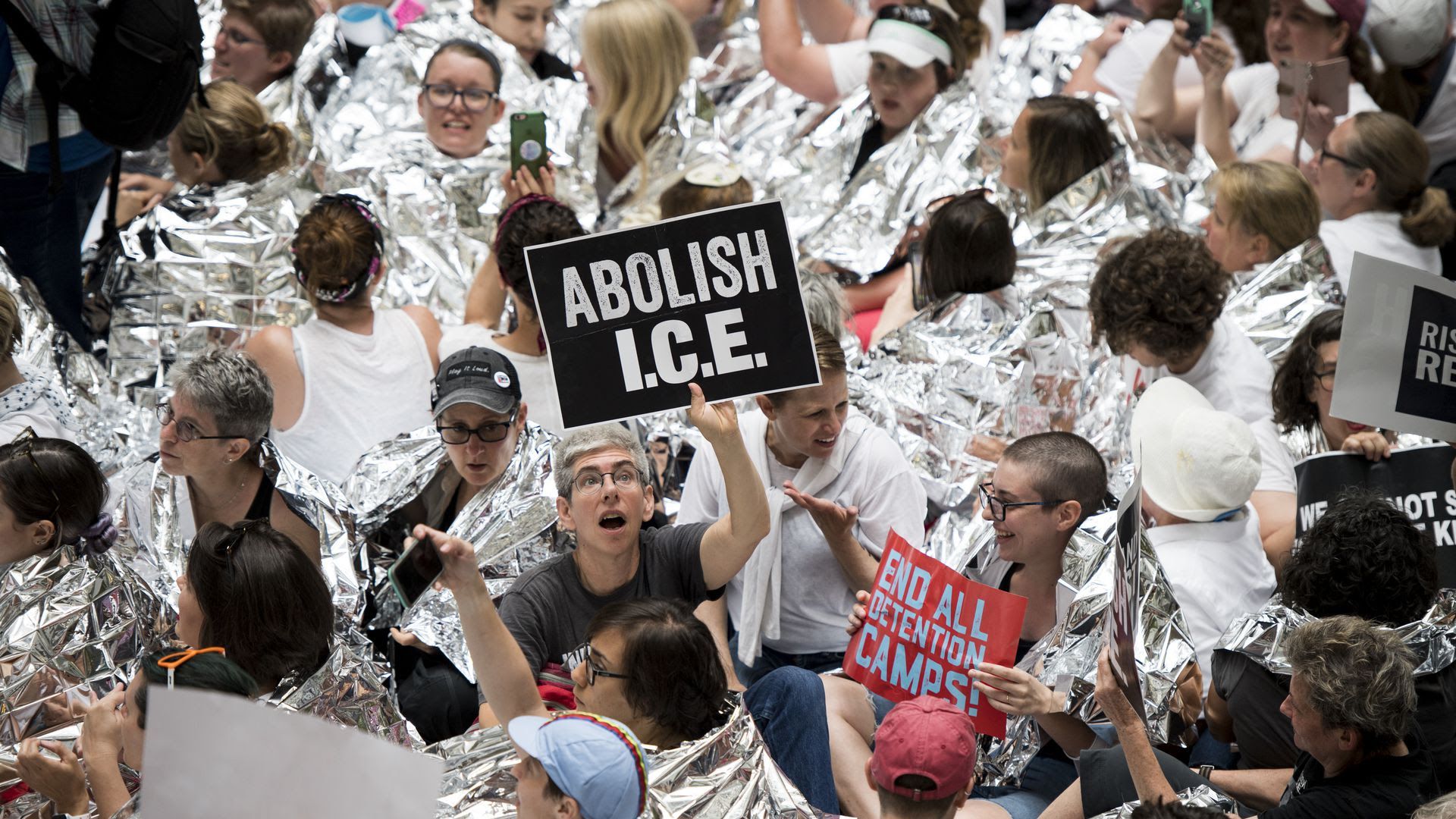 A person holds up a sign that reads "Abolish ICE." 