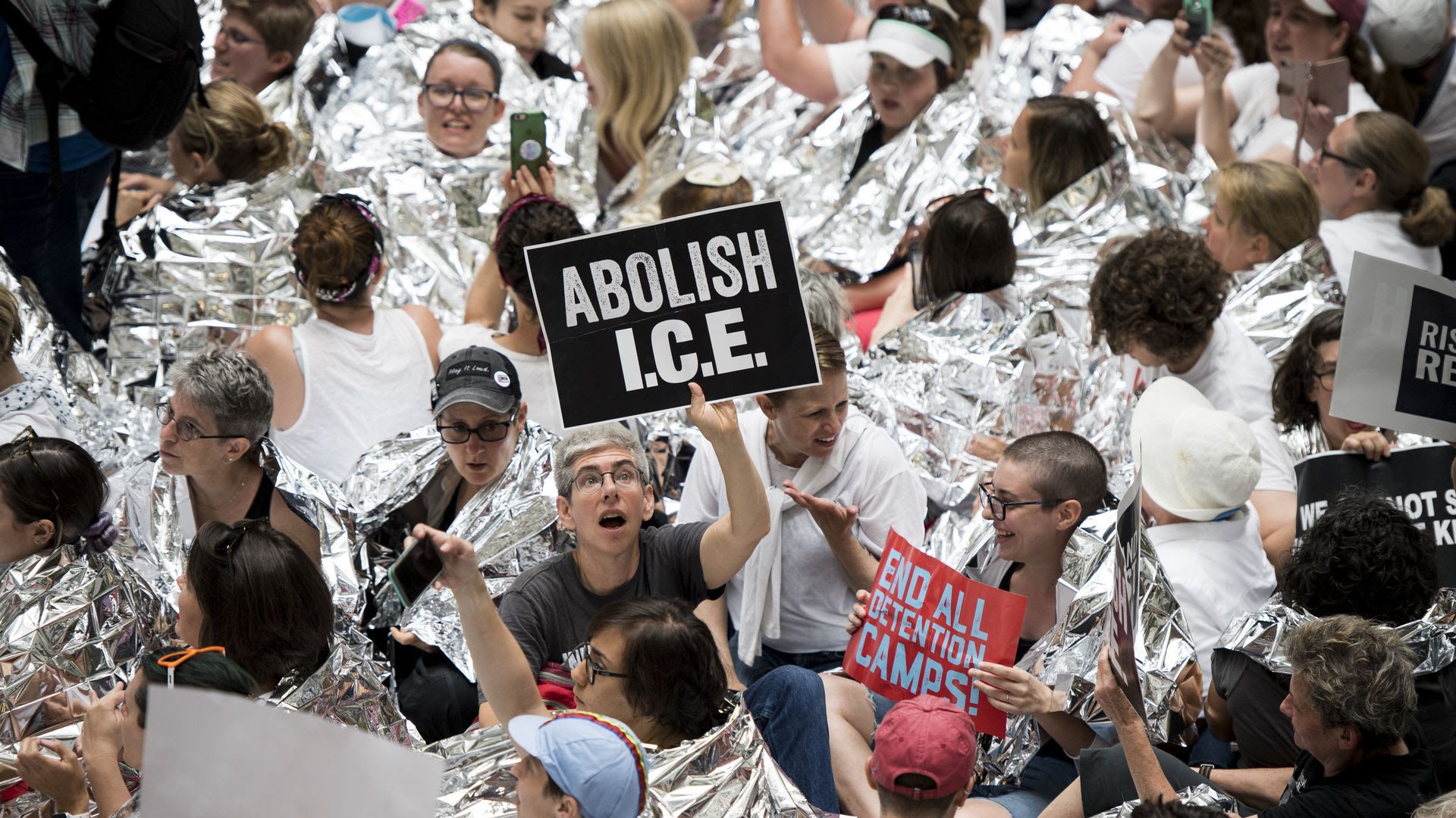 A person holds up a sign that reads "Abolish ICE."