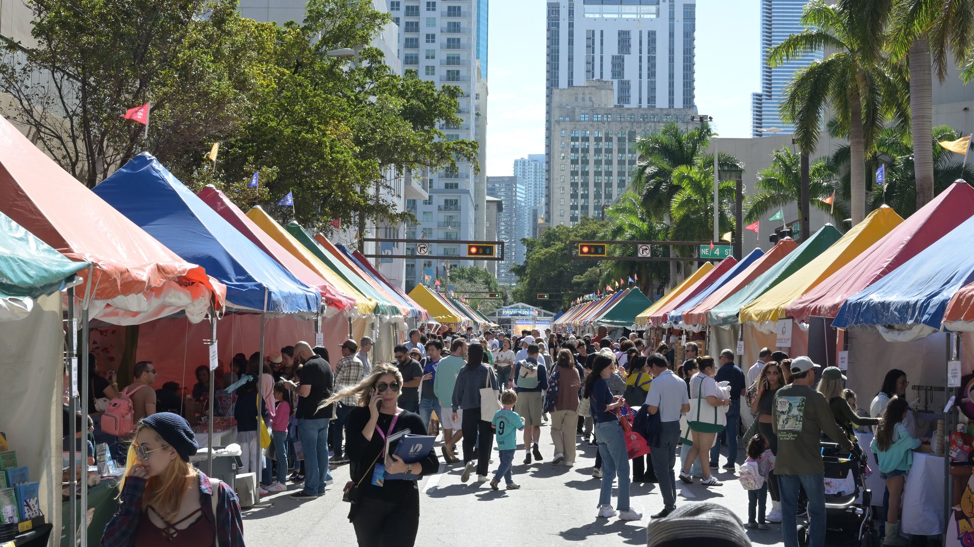 A crowd of people in front of tents and street fair vendors.