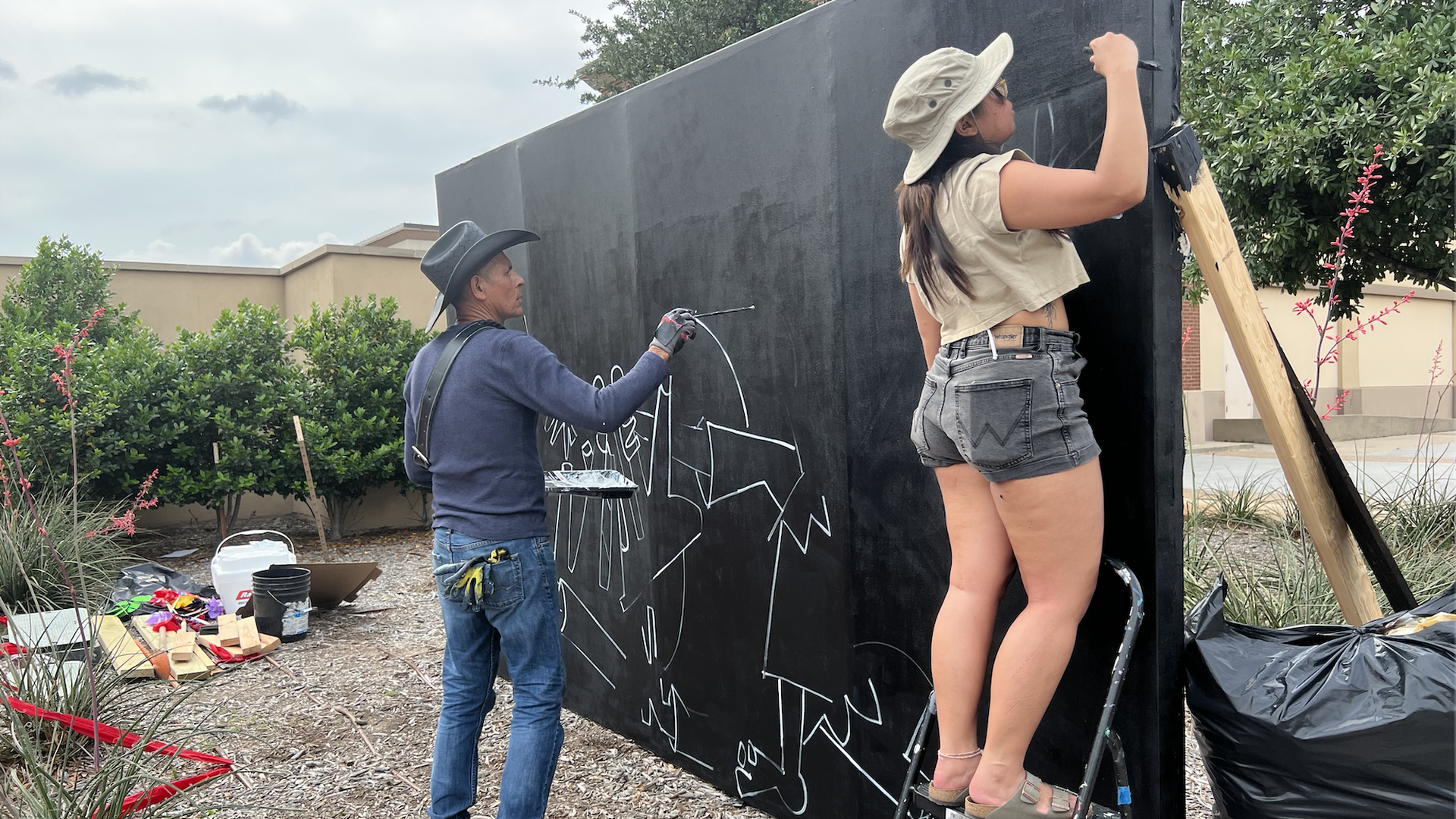 Two people work on a mural to commemorate the victims of the Allen shooting.