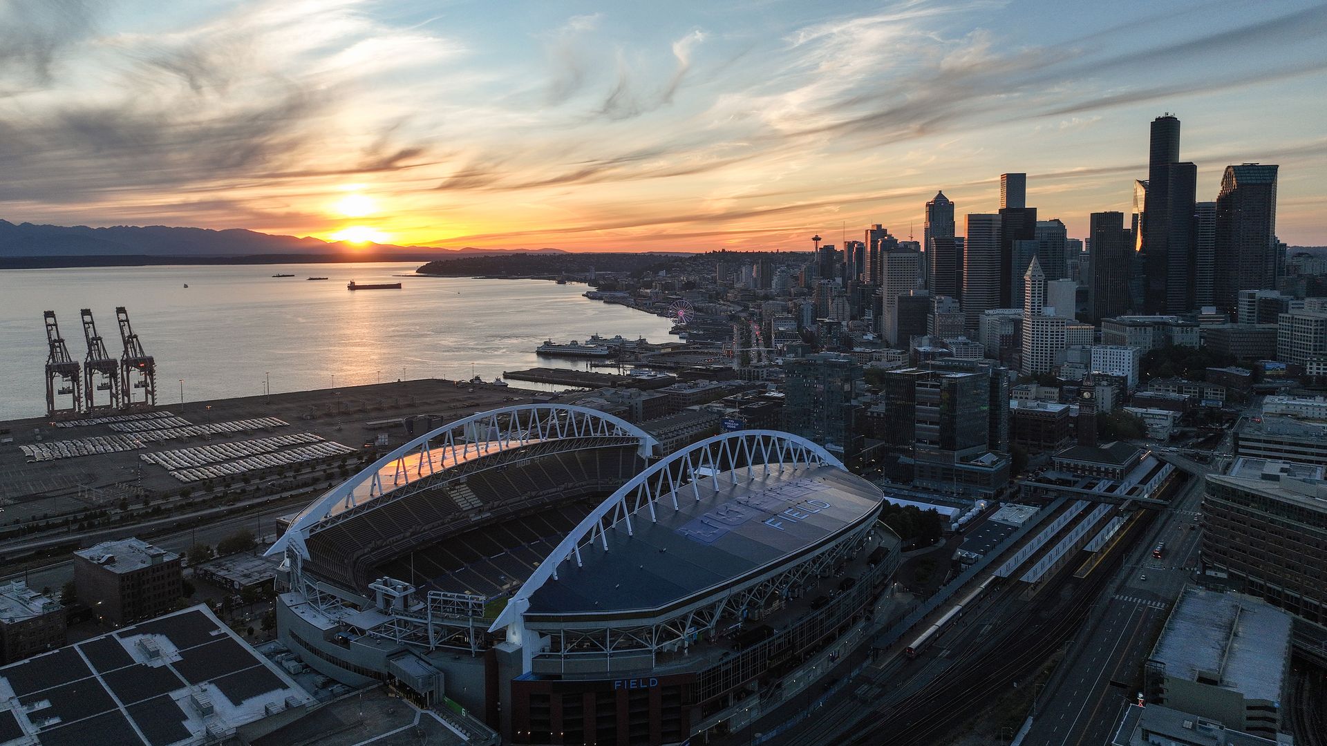 Seattle's white ribbed stadium seen against the city at sunset.