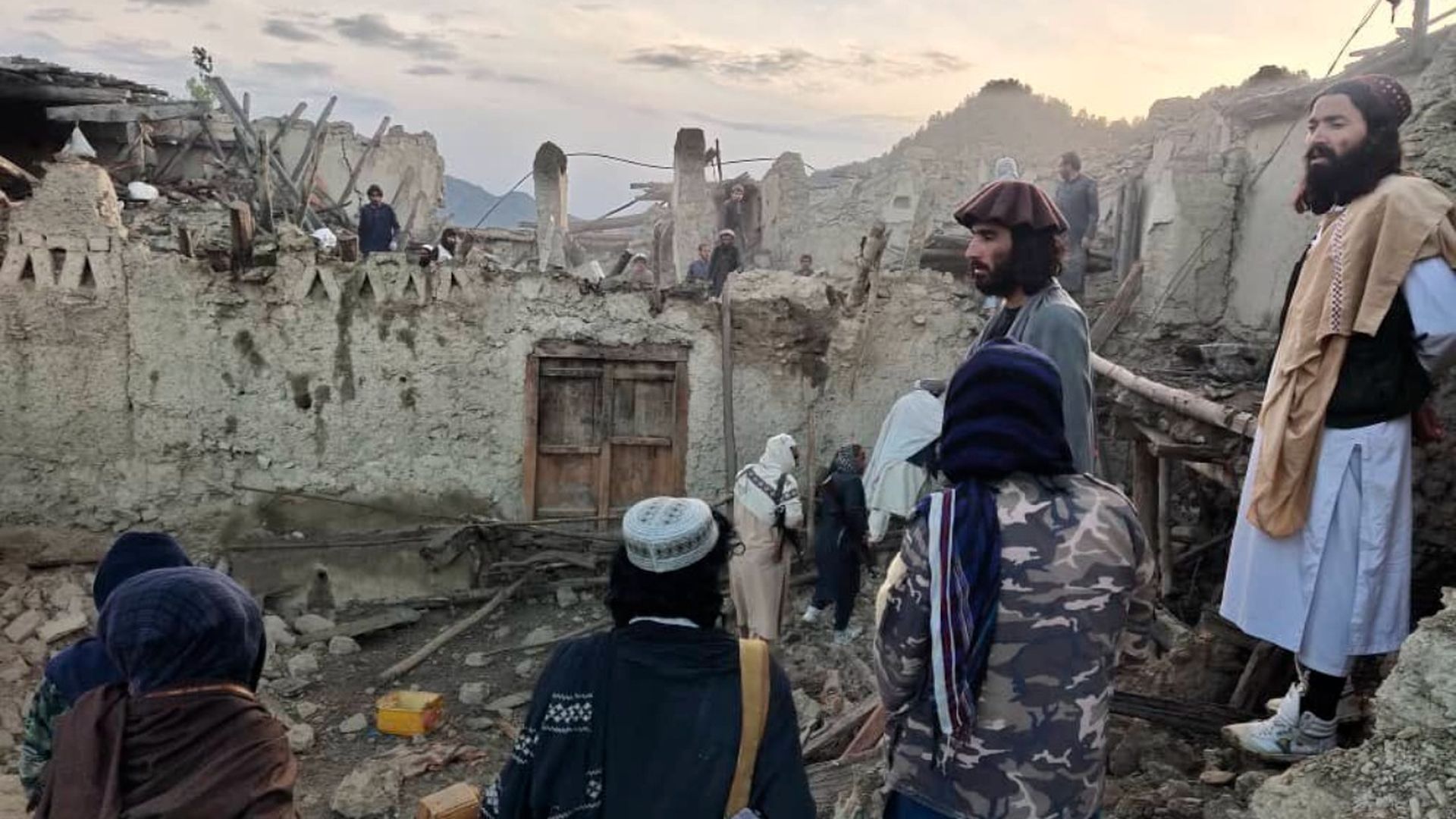 In this photo released by a state-run news agency Bakhtar, Afghans look at destruction caused by an earthquake in the province of Paktika, eastern Afghanistan, Wednesday, June 22