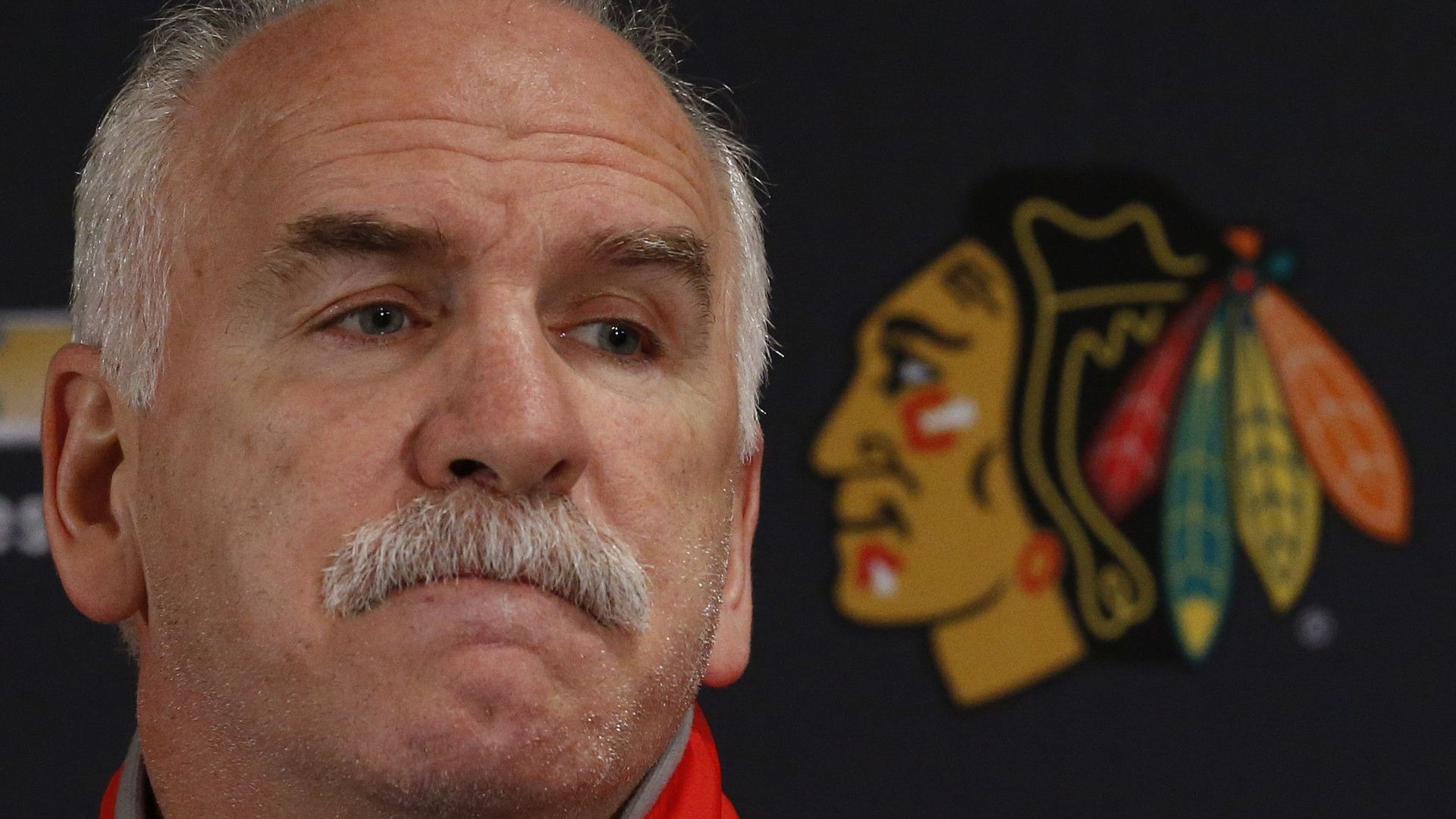 Joel Quenneville grimaces behind a podium.
