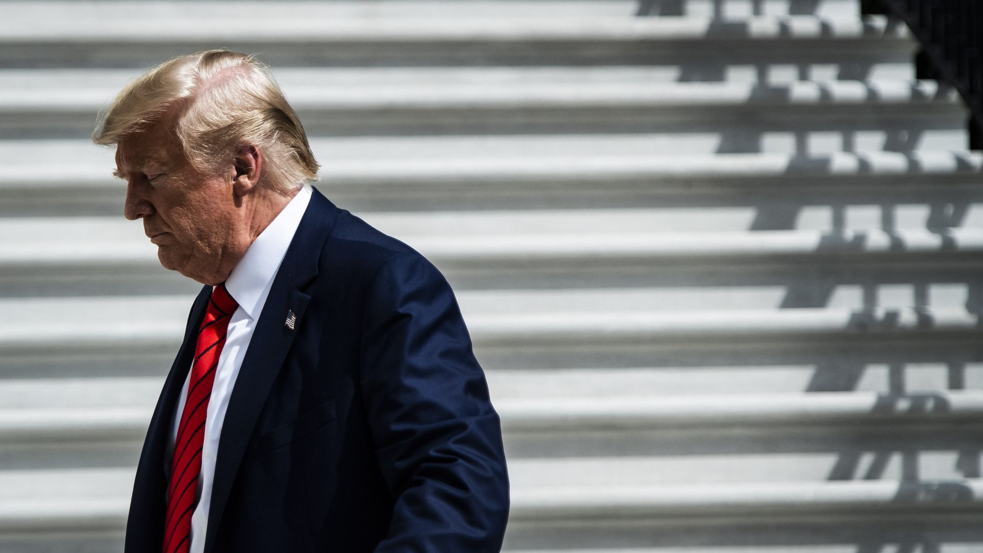 In this image, Trump walks down a flight of white stairs.