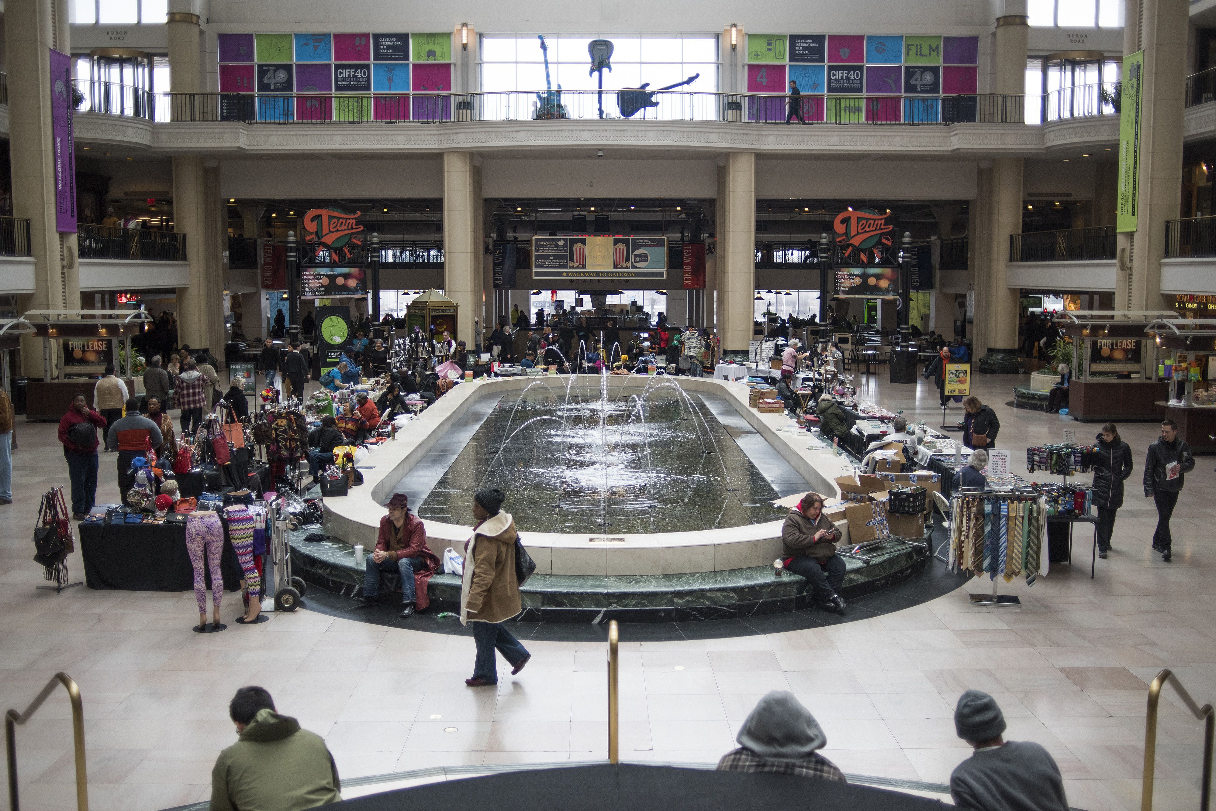 A mall with a fountain in the middle and shoppers around it