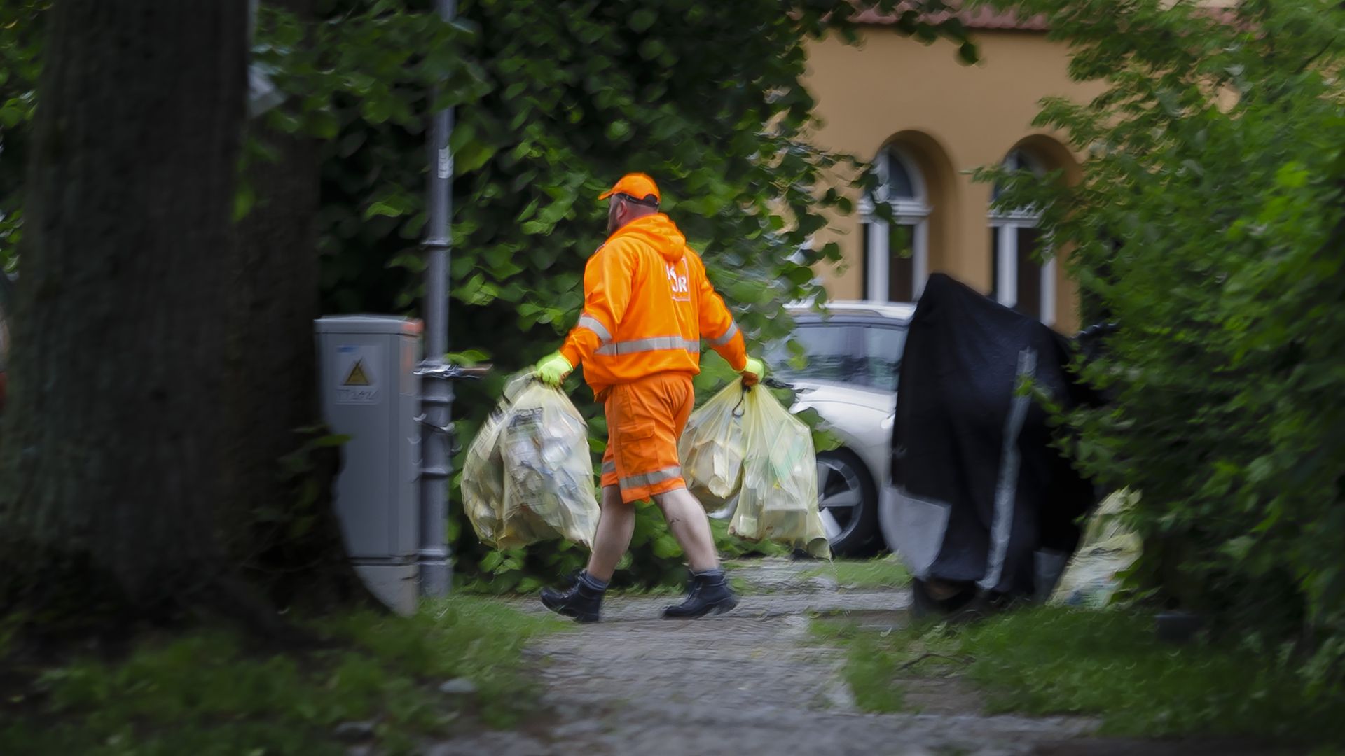 A garbage man carries bags of plastic waste for recycling 