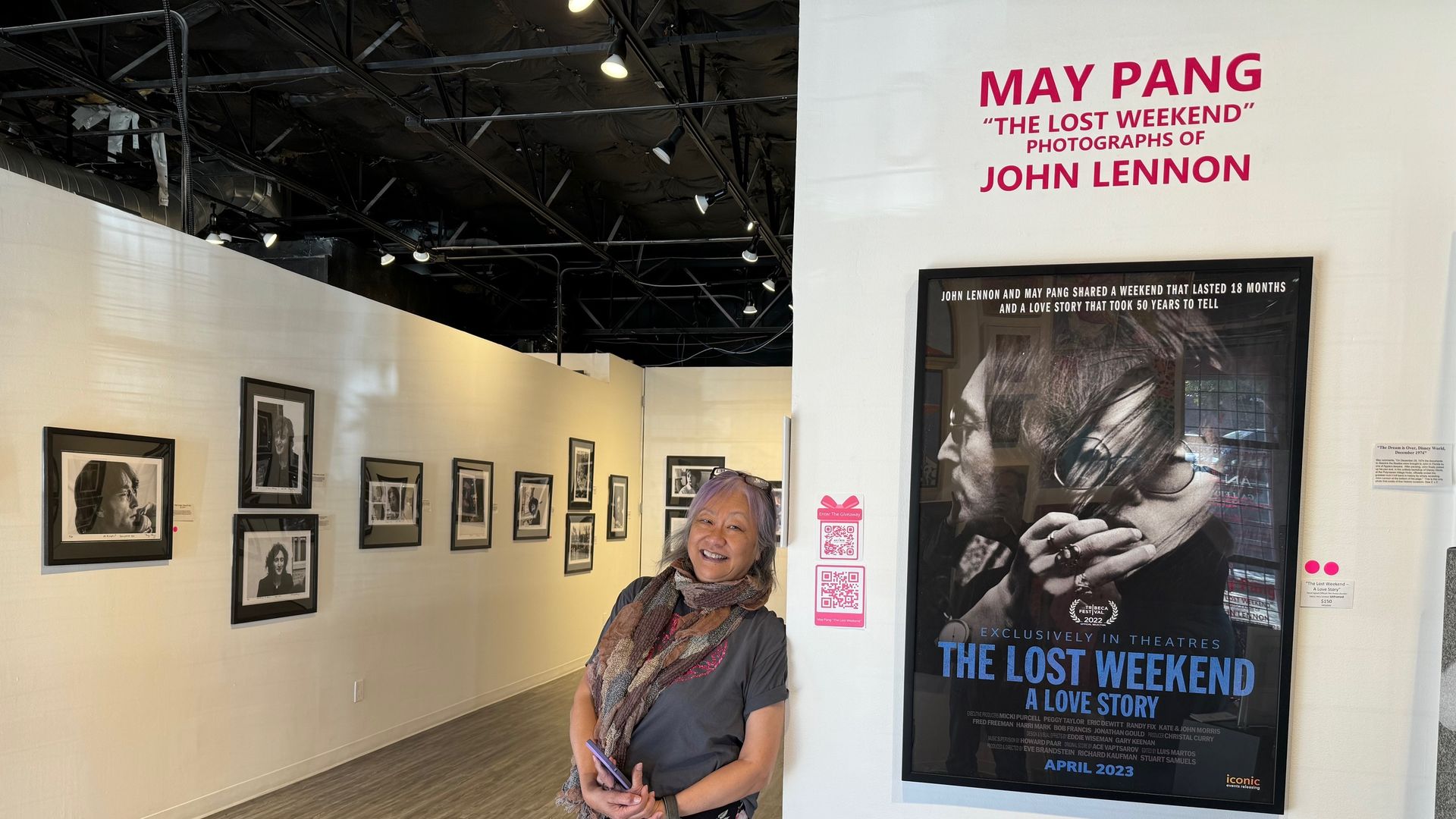 woman standing next to poster of John Lennon