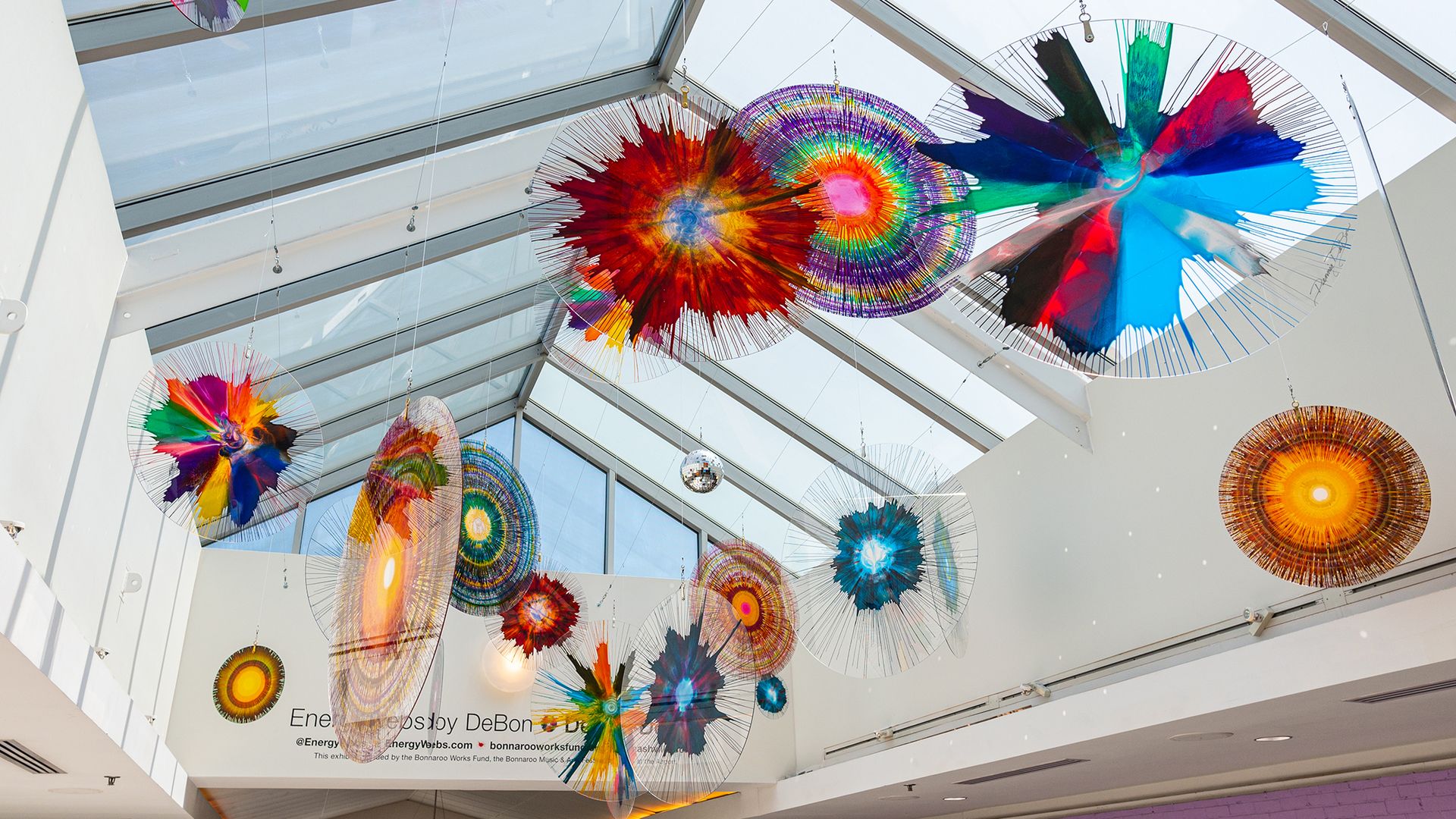 Colorful glass sculptures suspended in a skylight.