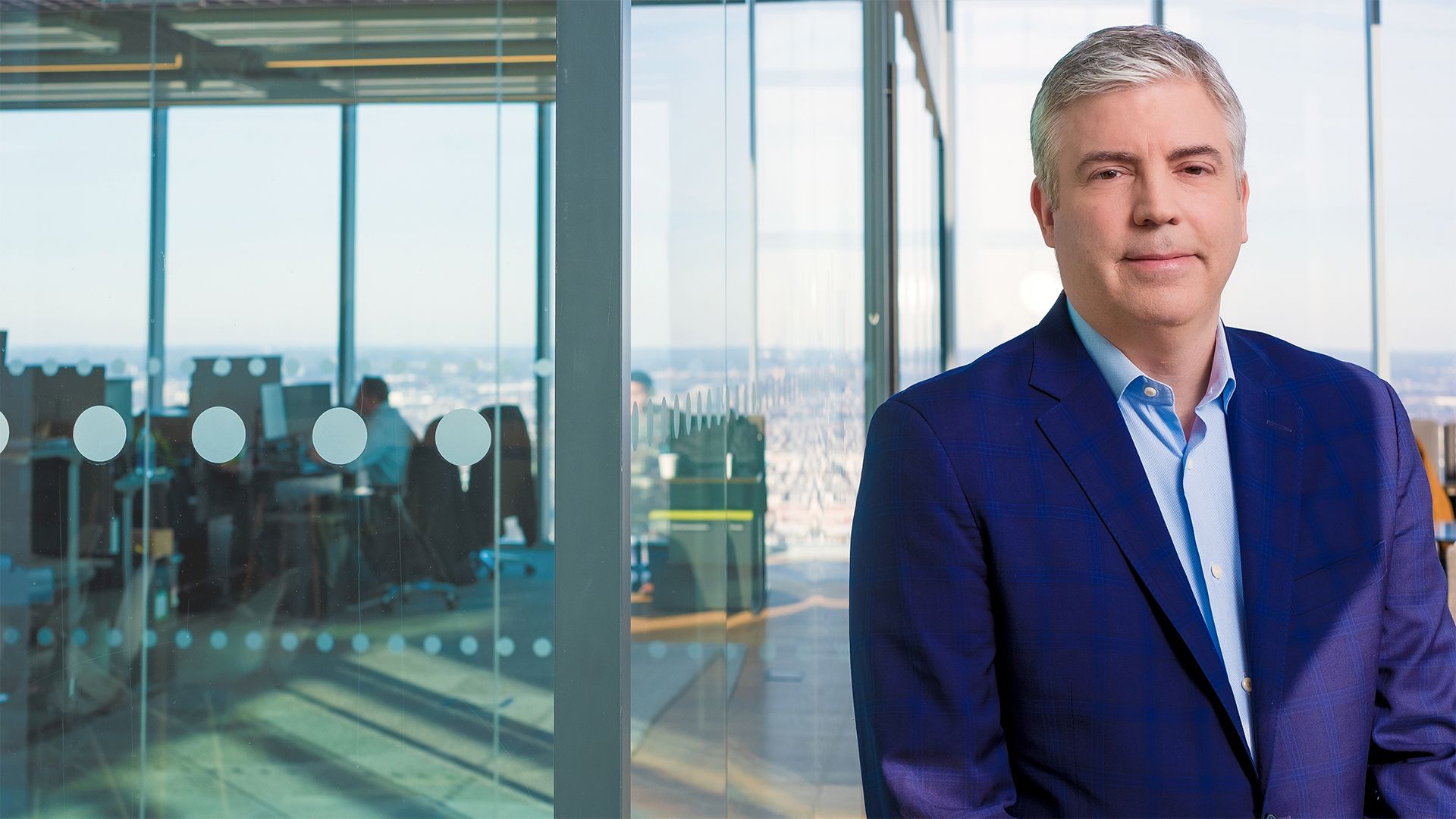 Marcien Jenckes in a photo by himself standing in front of a glass wall. 