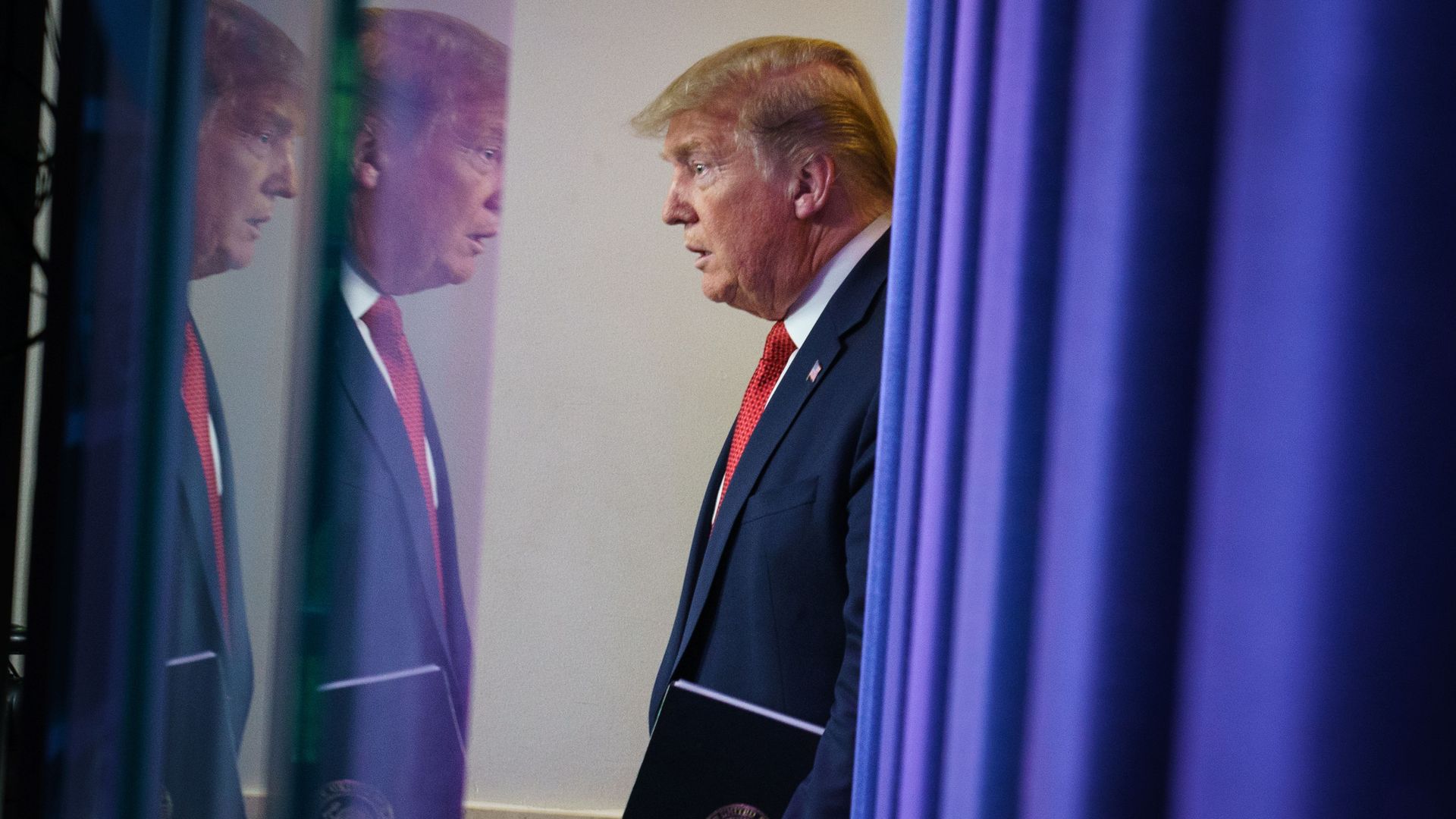 In this image, Trump stands in a mirror facing himself