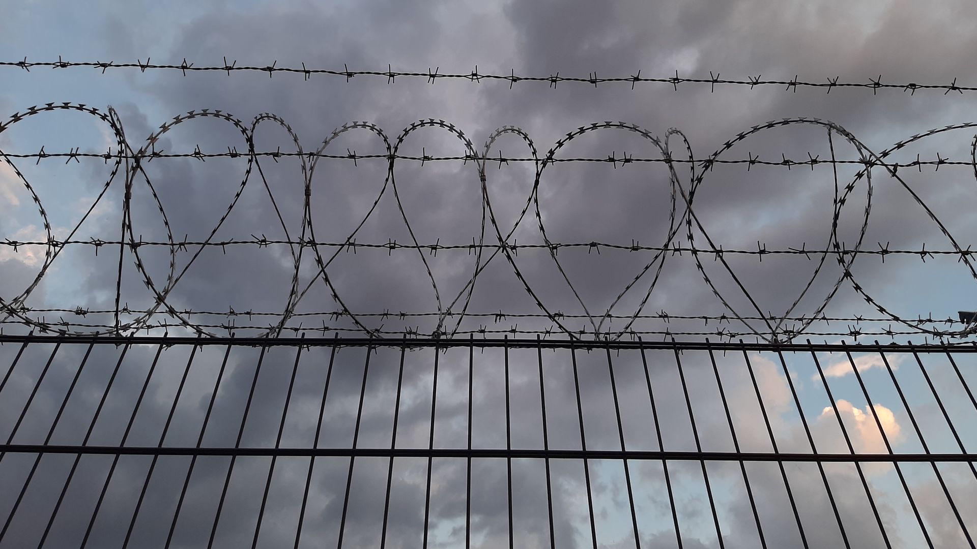 Photo of a jail fence with barbed wire.