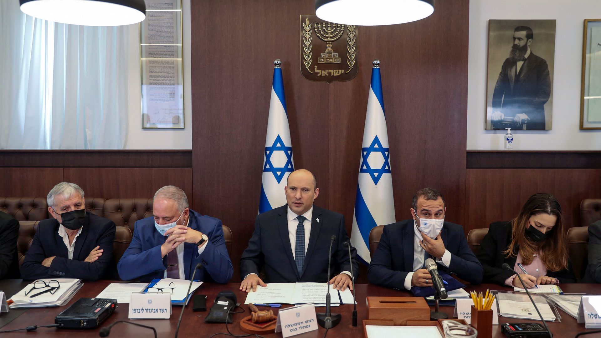 Photo of Naftali Bennett (center) sitting at a table with people on his left and right