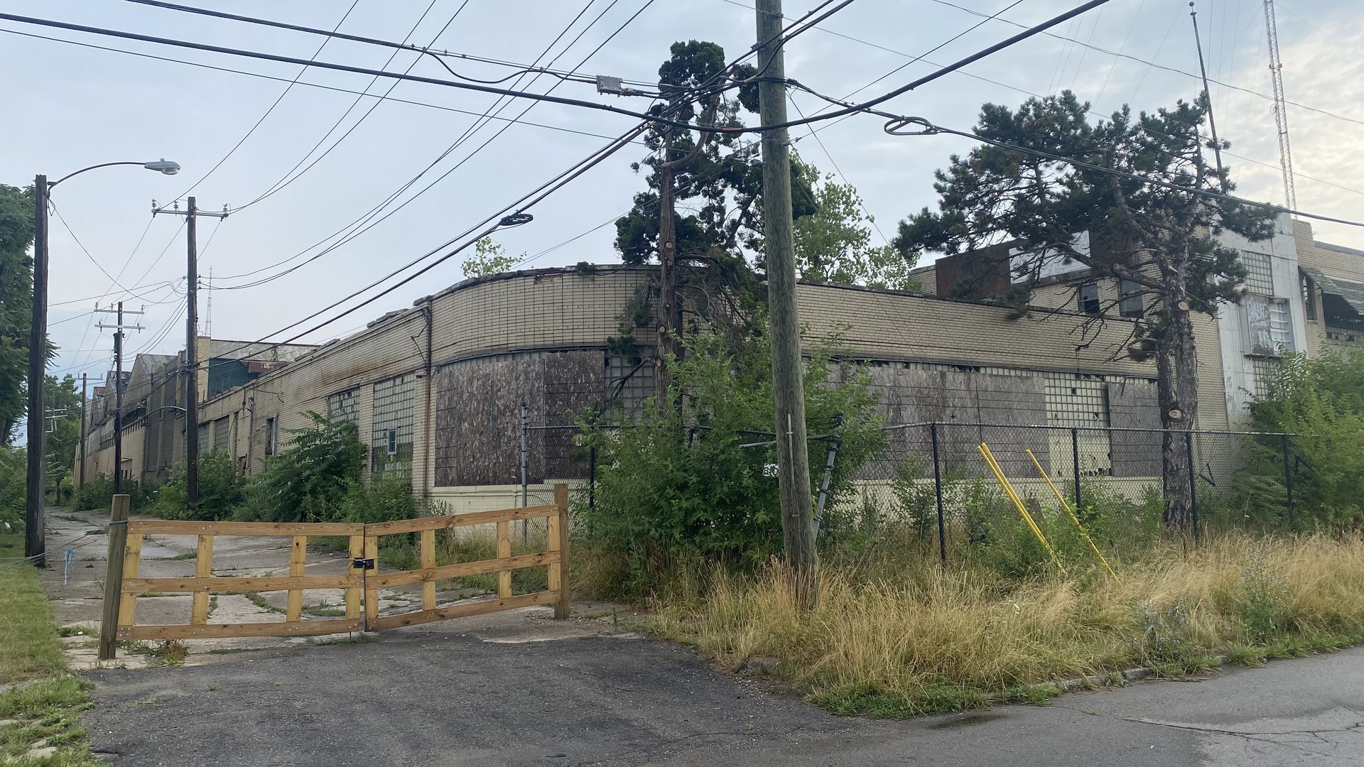 A long-vacant, sprawling complex is pictured from the road with boarded up windows.