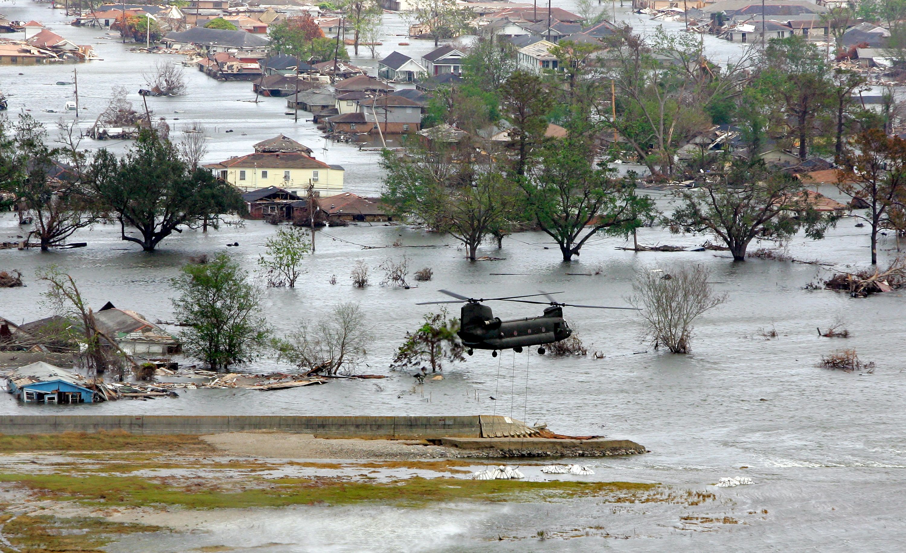 helicopter flies over a flooded area of homes