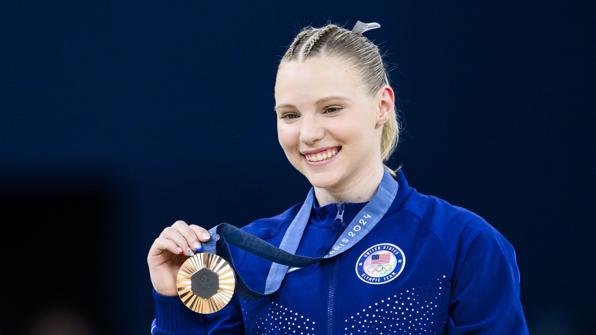 A photo of a person smiling and holding a bronze medal.