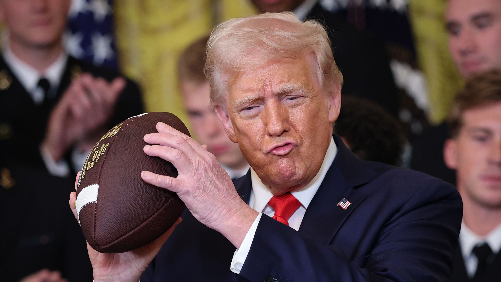 Trump is holding a football like he's preparing to pass in a collapsing pocket