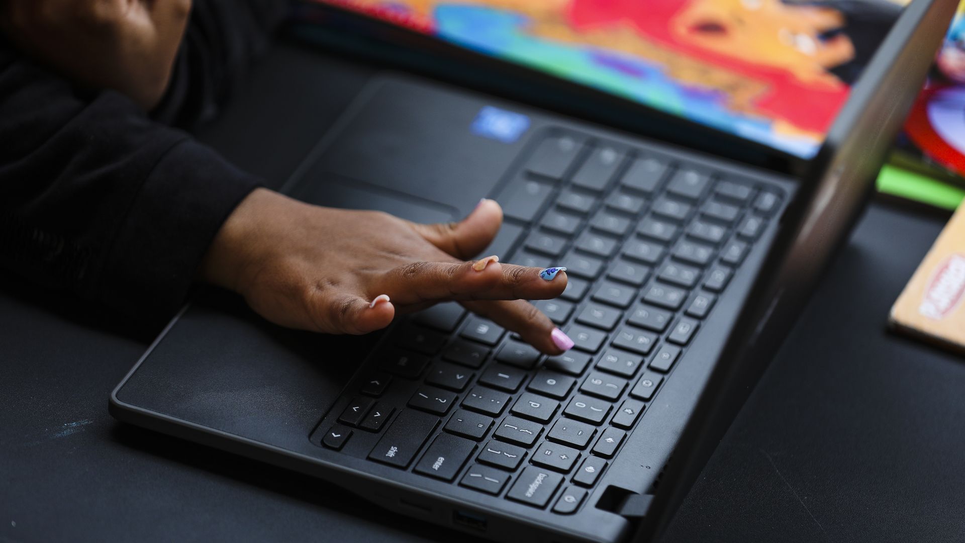a hand pressing a key on a laptop keyboard