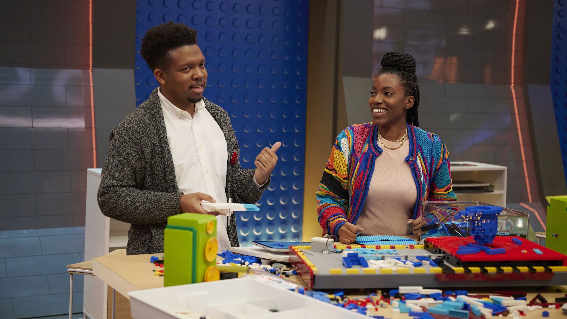 Picture of two contestants in Fox's "Lego Masters," they are standing by a table with a bunch of legos on it