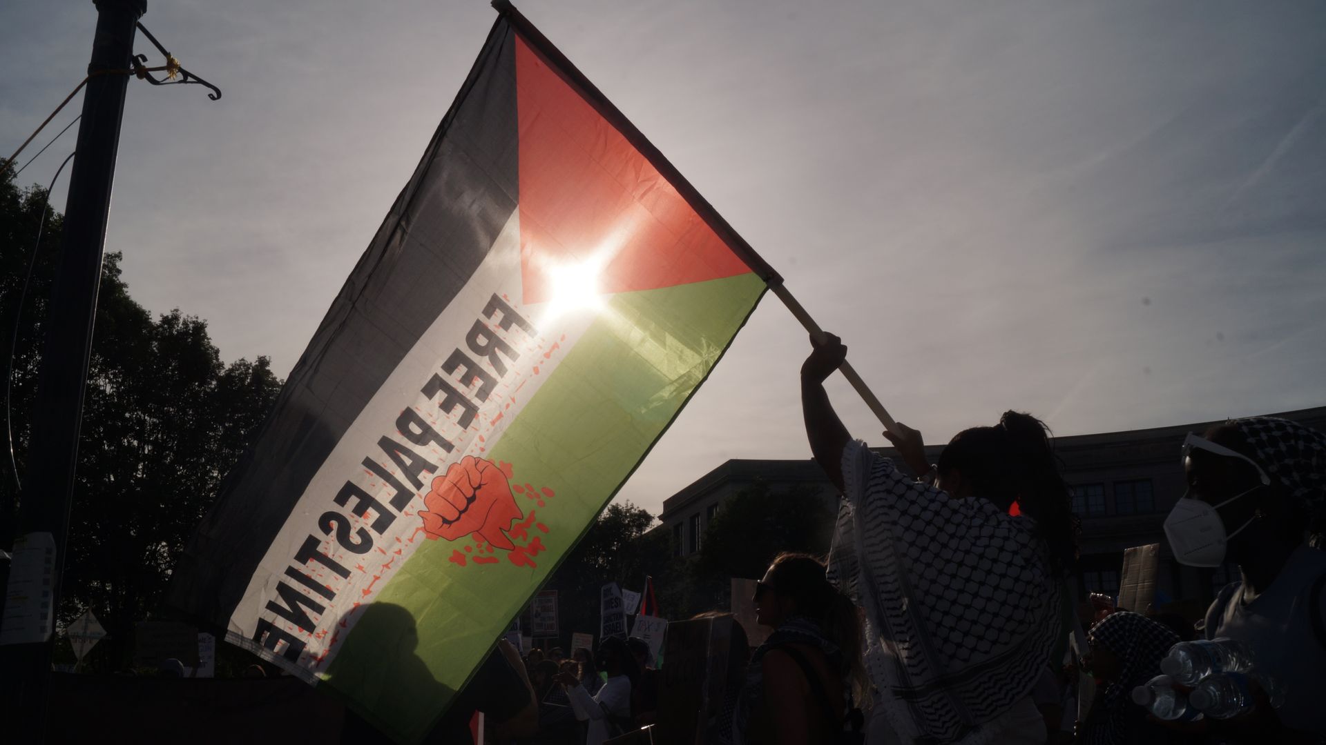 A "free Palestine" flag waving in the setting sun. 