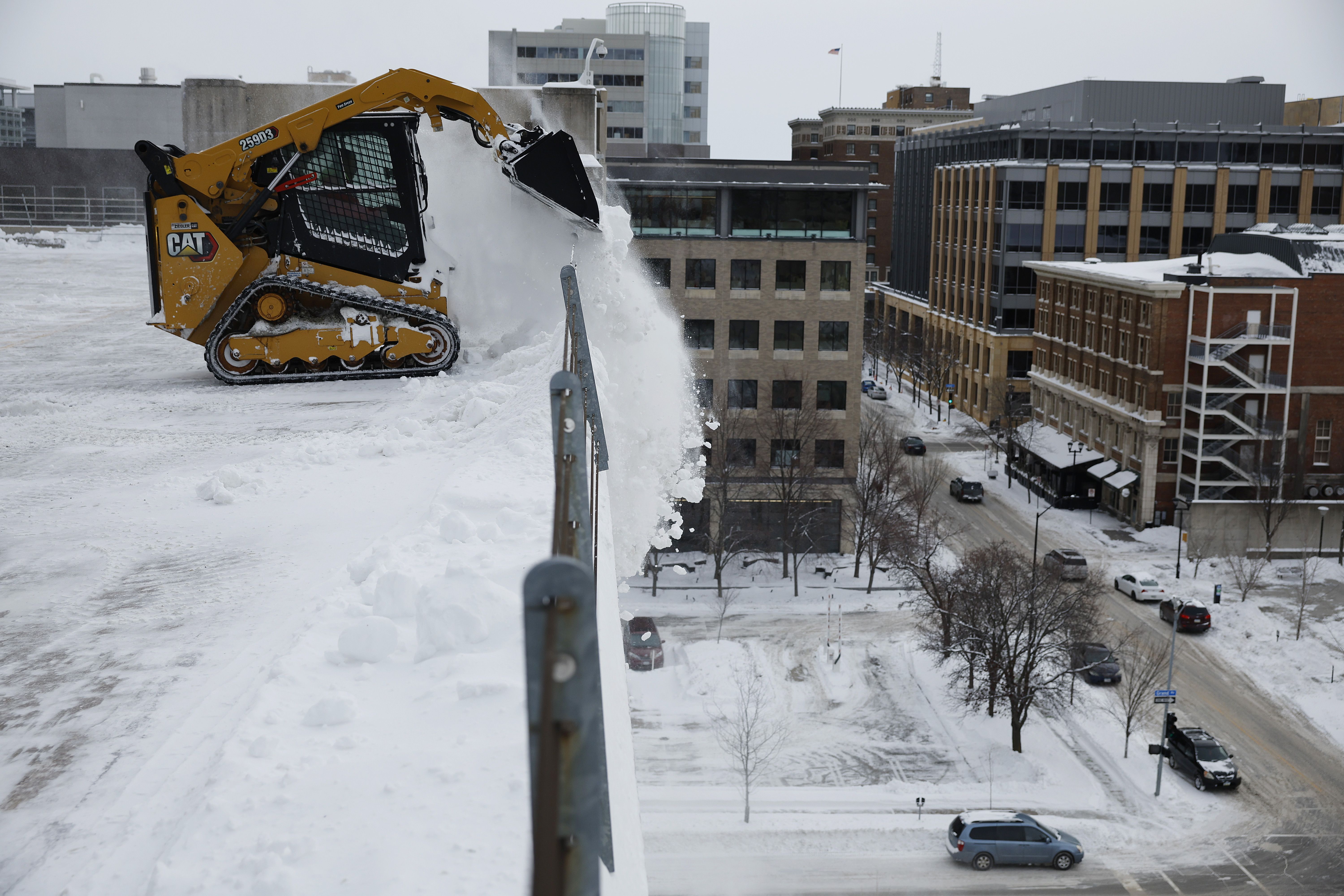 Track loaders are used to shovel and dump snow off of the top of a parking garage as sub-freezing temperatures continue on January 15, 2024 in Des Moines, Iowa. Iowans vote today in the state’s caucuses for the first contest in the 2024 Republican presidential nominating process.