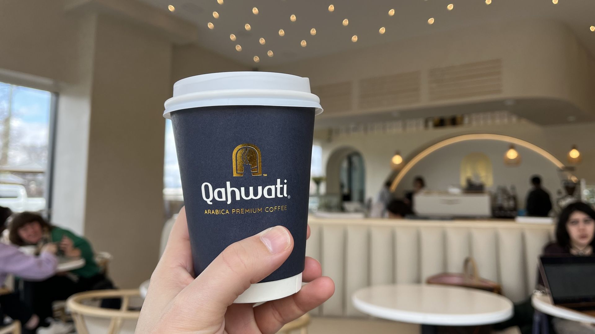 Joe hold's his Nomad latte inside Qahwati.