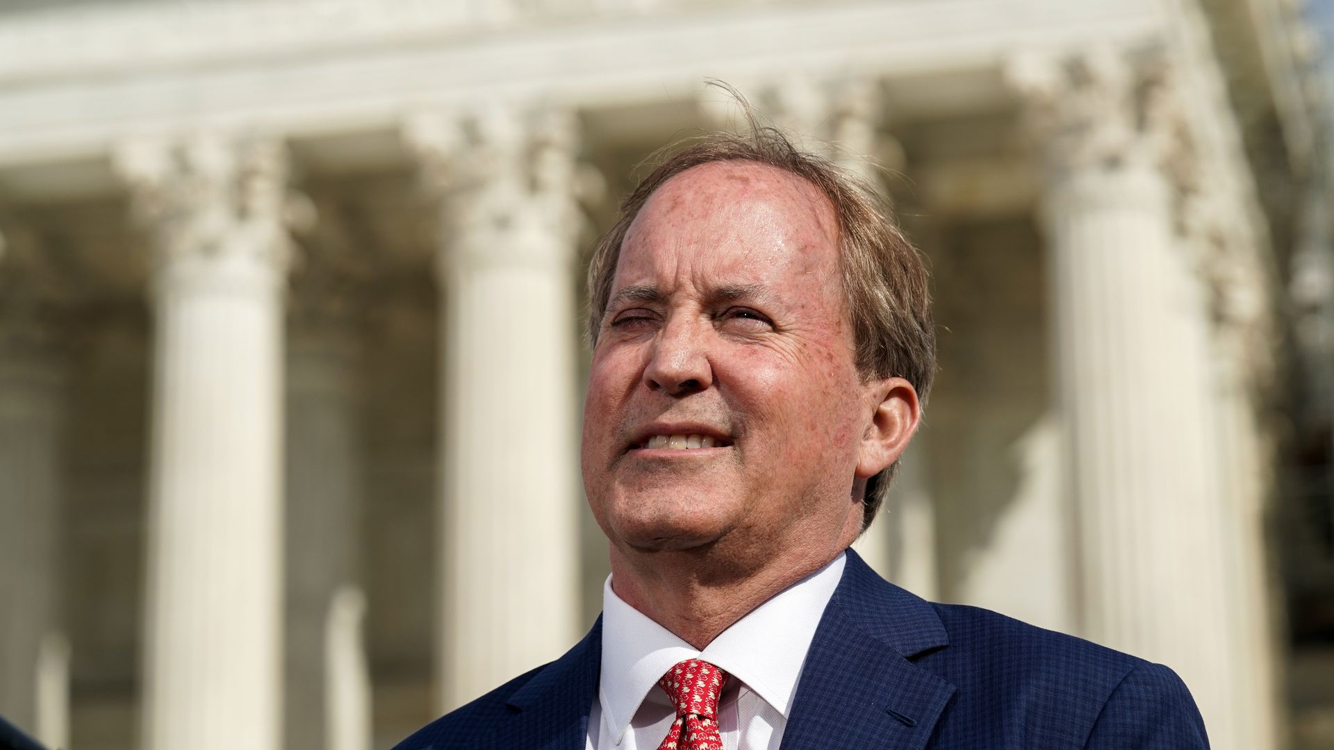 A photo of Texas Attorney General Ken Paxton standing in front of a building with columns