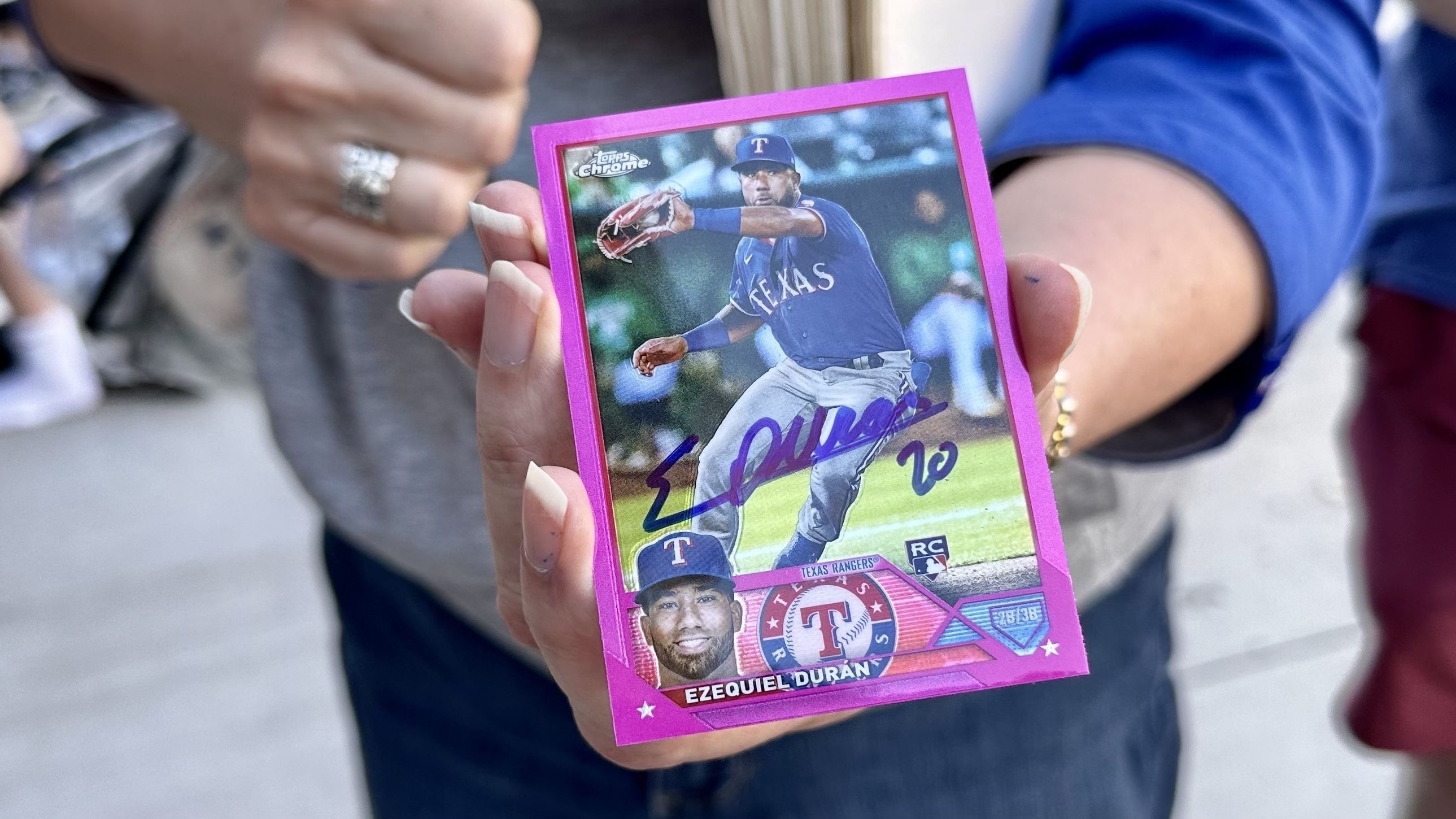 A woman holds up a signed baseball card