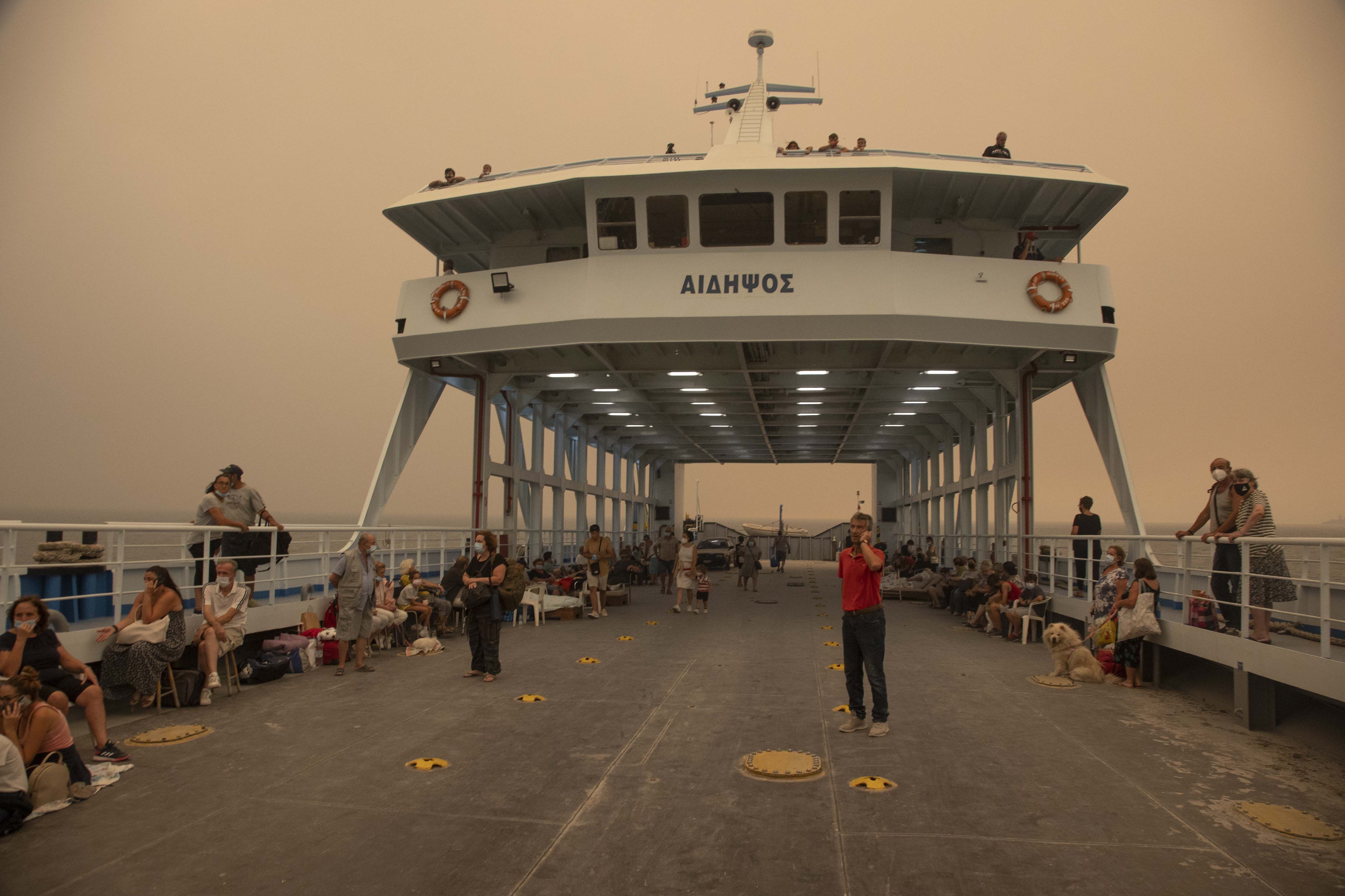 A ferry hosting people who can't evacuate in Greece, surrounded by a hazy orange sky 