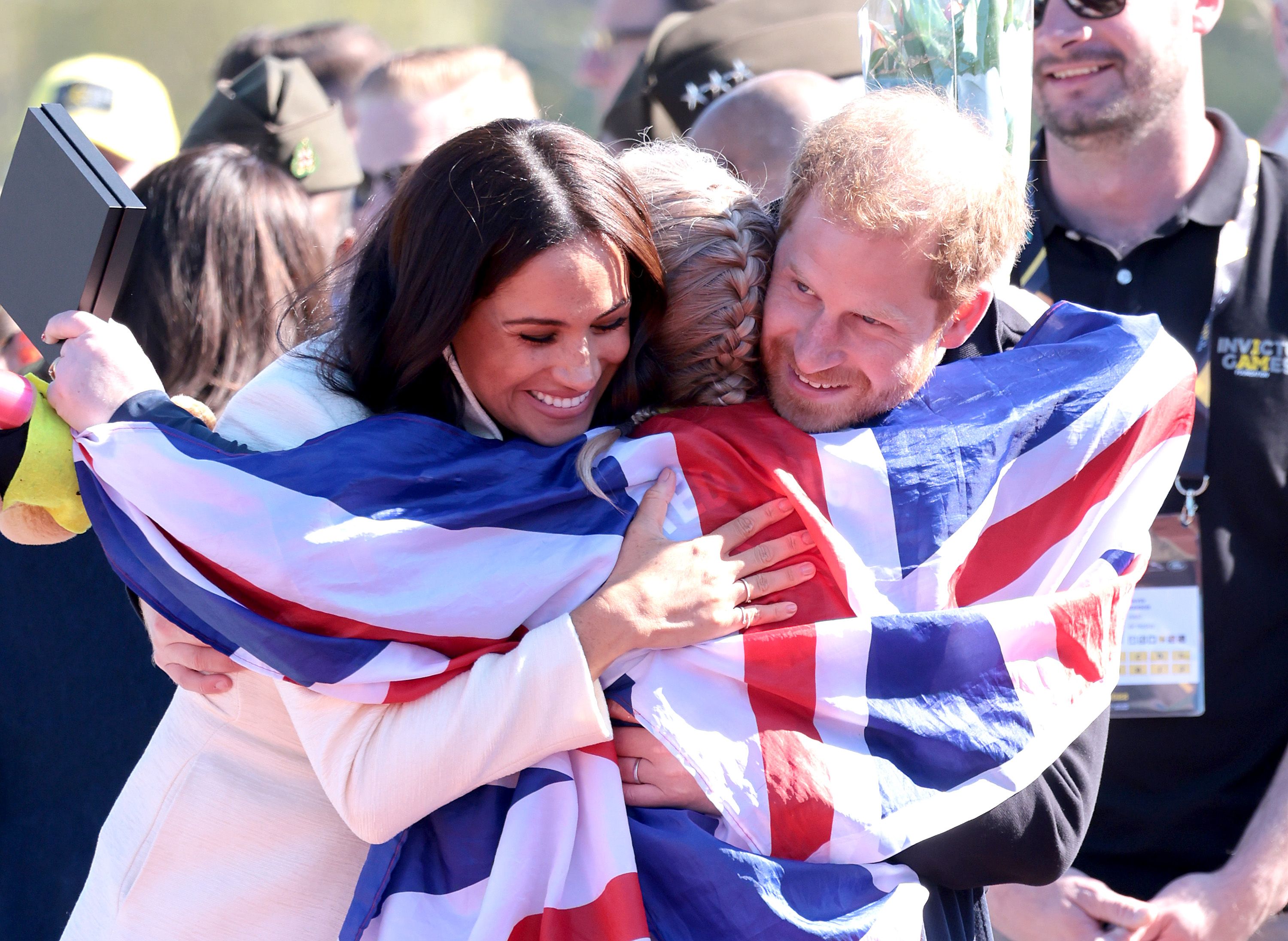 Prince Harry and Meghan Markle hugging an athlete