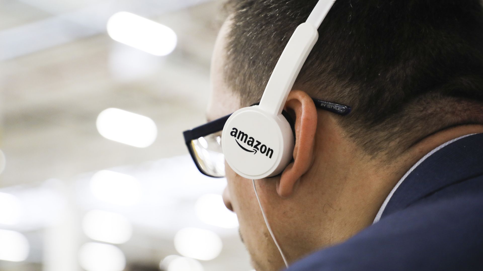 In this image, a man wears headphones with the Amazon logo.