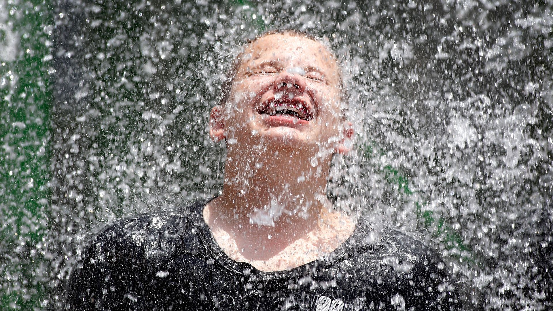 A boy is sprayed with water at a water park. 